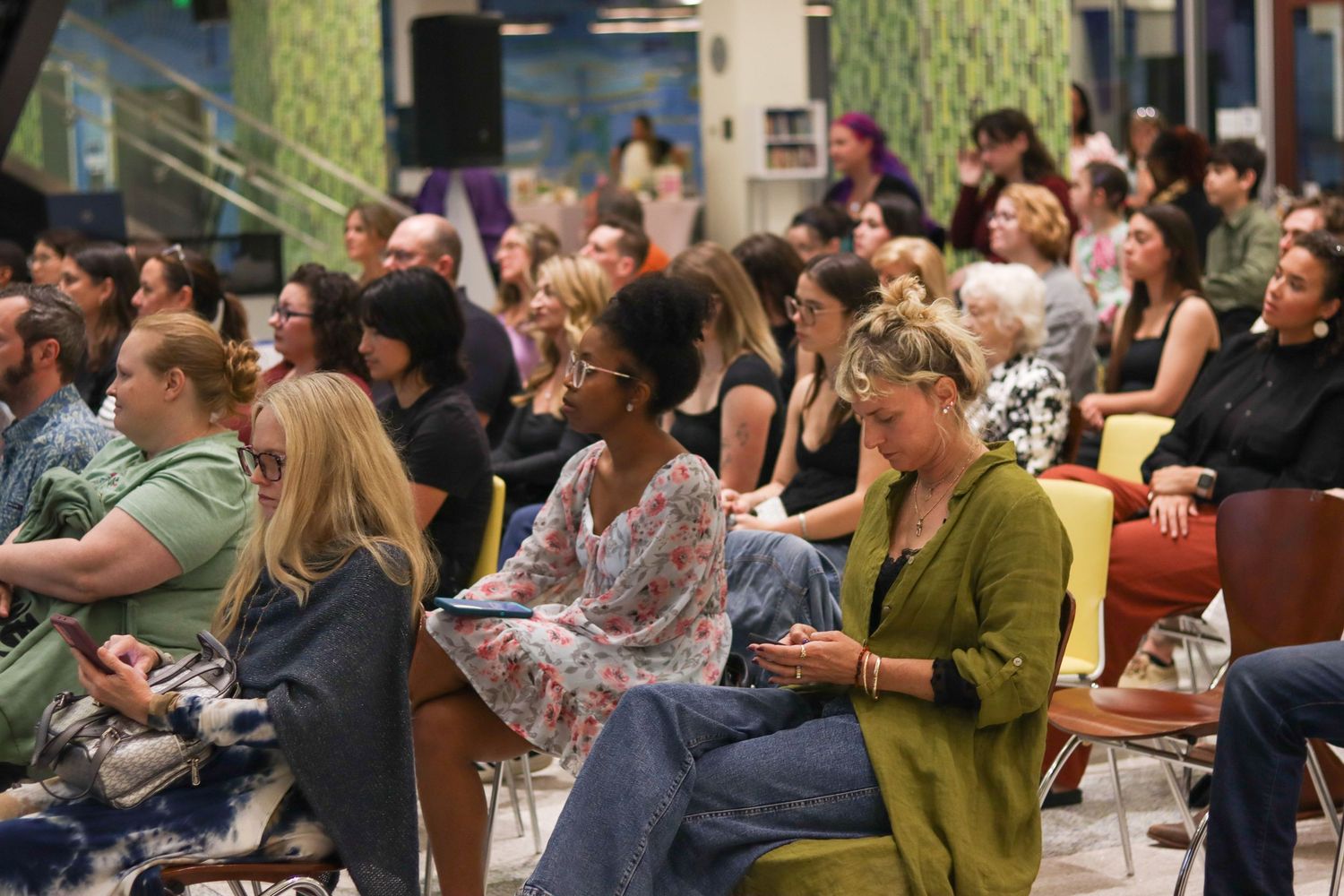 Large diverse audience seated attentively at Bridges arts performance event in modern venue.