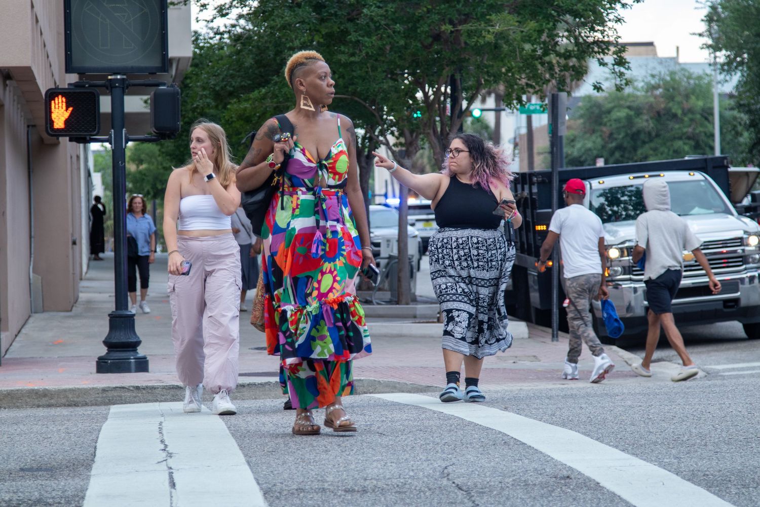 Group of people crossing a city street intersection during an outdoor evening event.