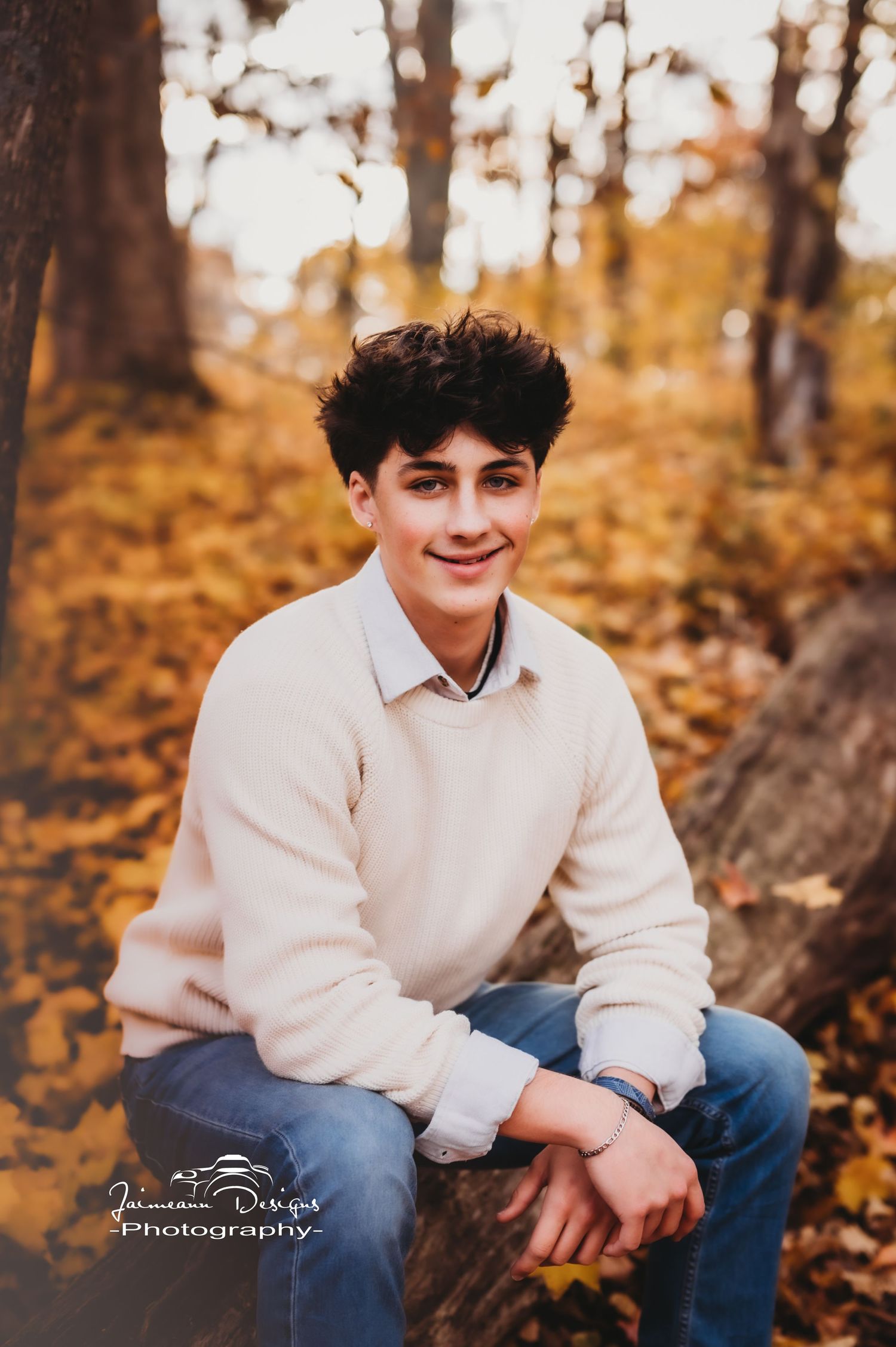 Outdoor portrait with cream sweater against warm autumn forest backdrop.