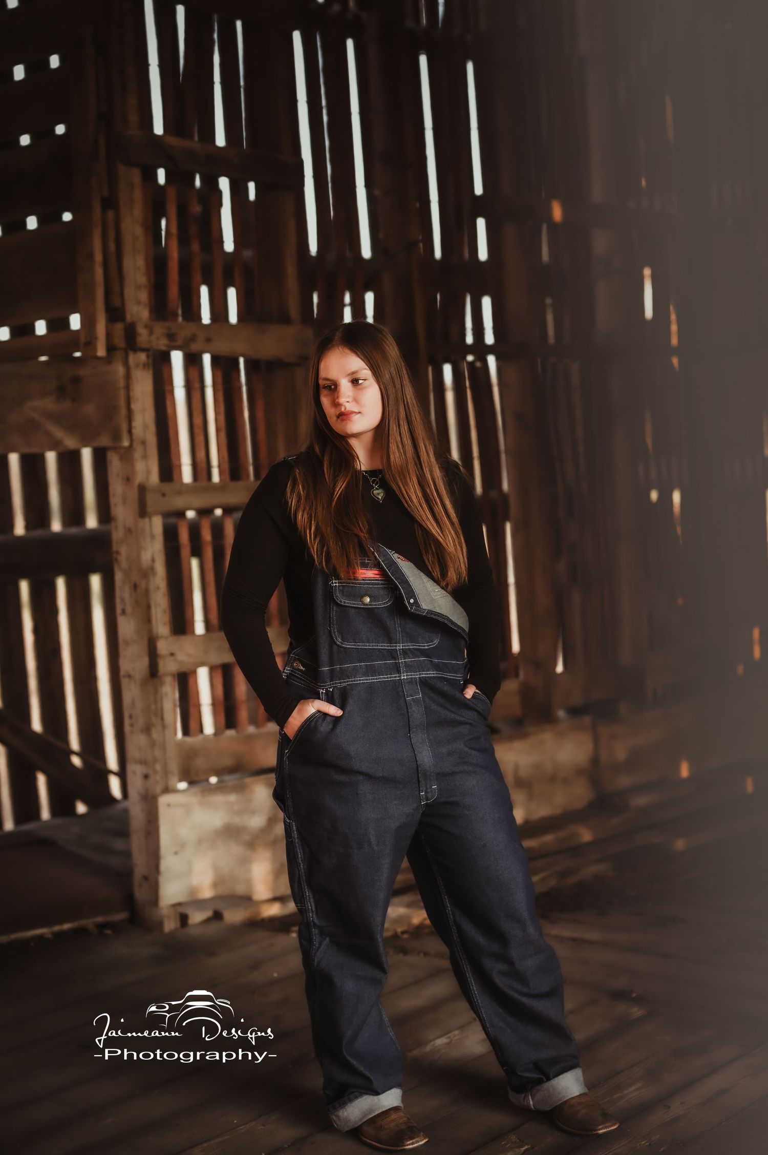 Artistic portrait in barn interior with dramatic light streaming through wooden slats.