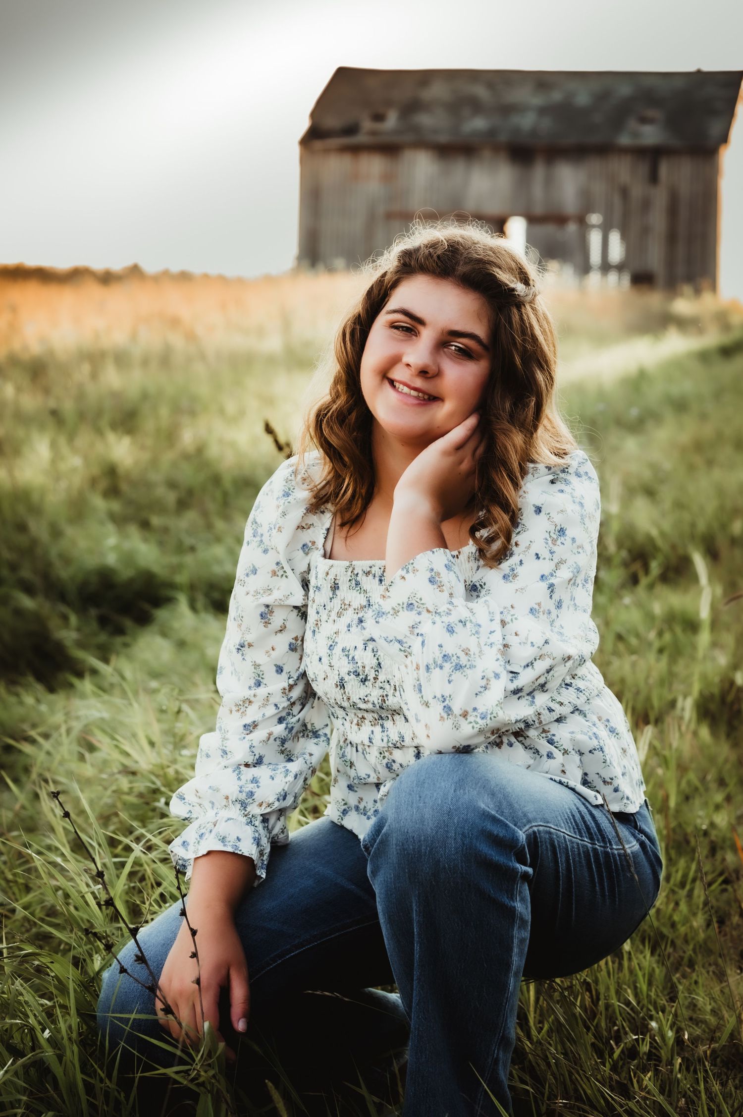 Candid outdoor portrait in field with rustic barn and natural lighting.