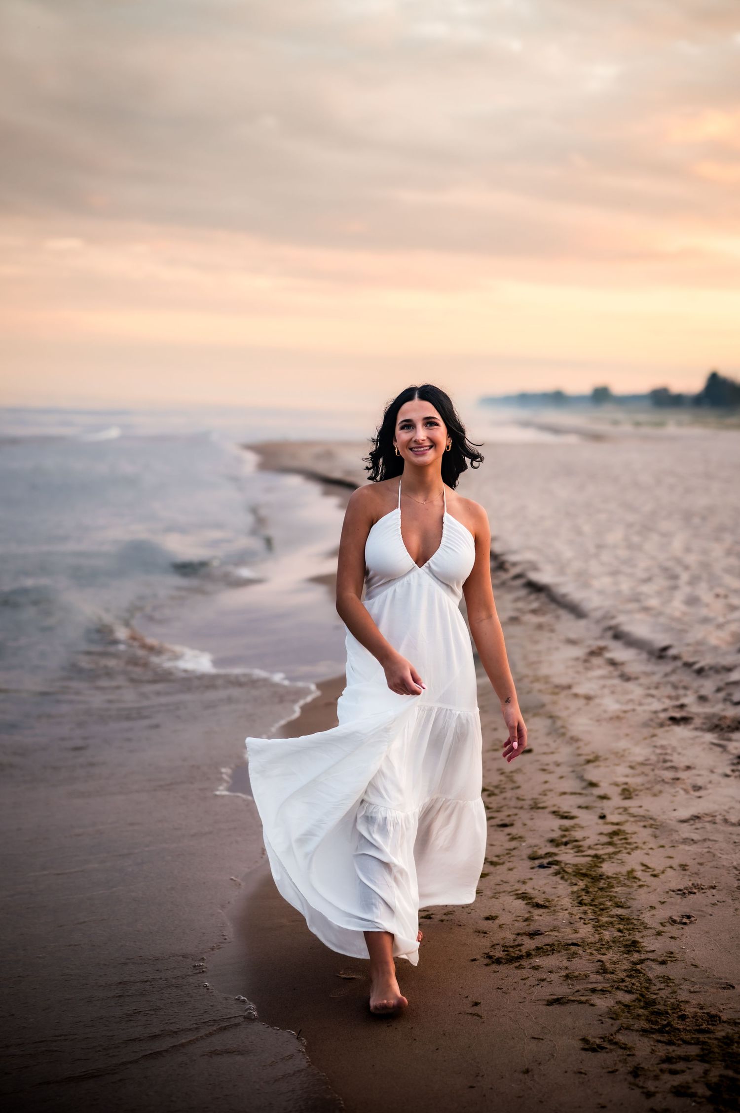 A woman in a flowing white dress runs joyfully along a beach shoreline at sunset on Sheboygan Kohler Andre Park, Wi