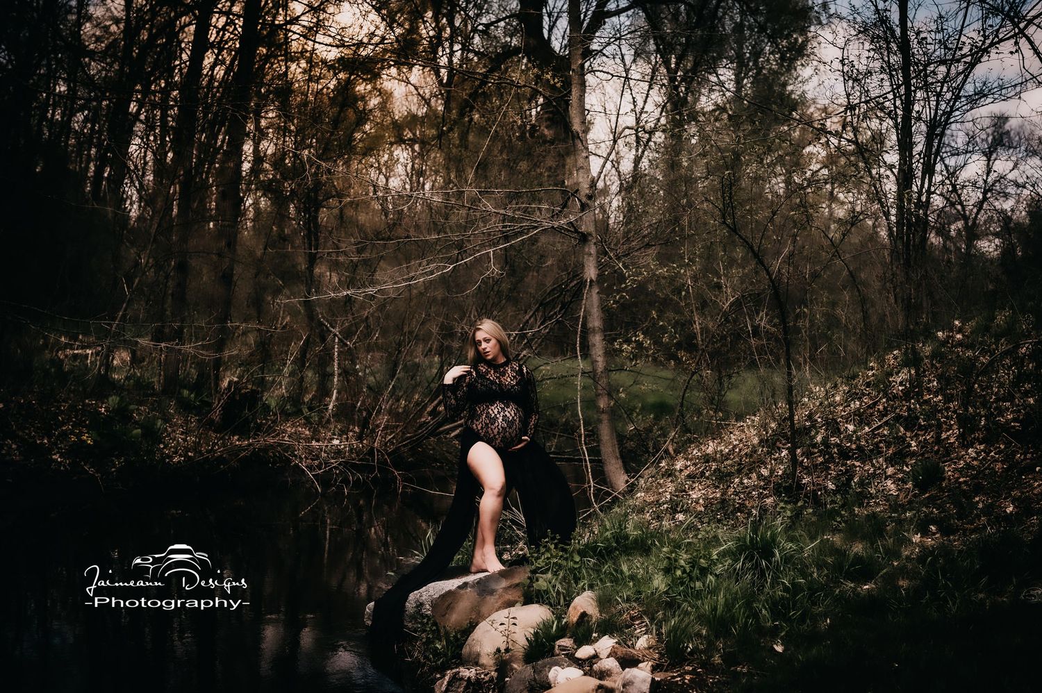 Artistic maternity photo by forest stream with natural lighting.