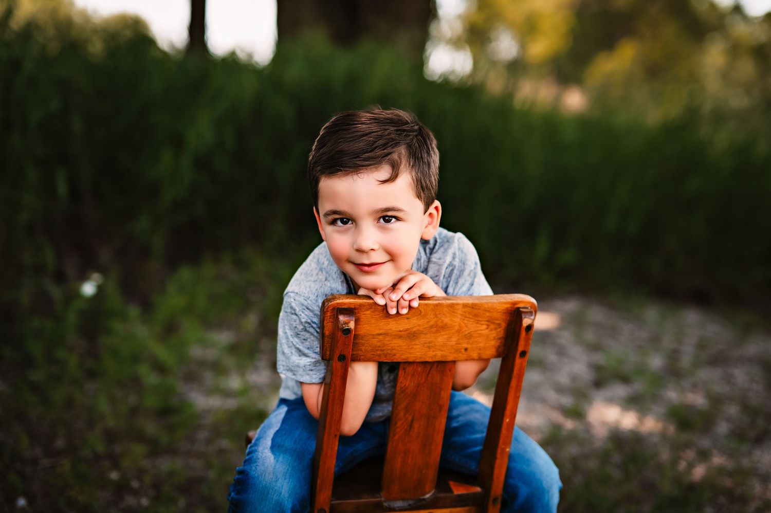 A child in blue sits outdoors with a vintage brown leather suitcase in a natural setting outdoor studio near West Bend, WI