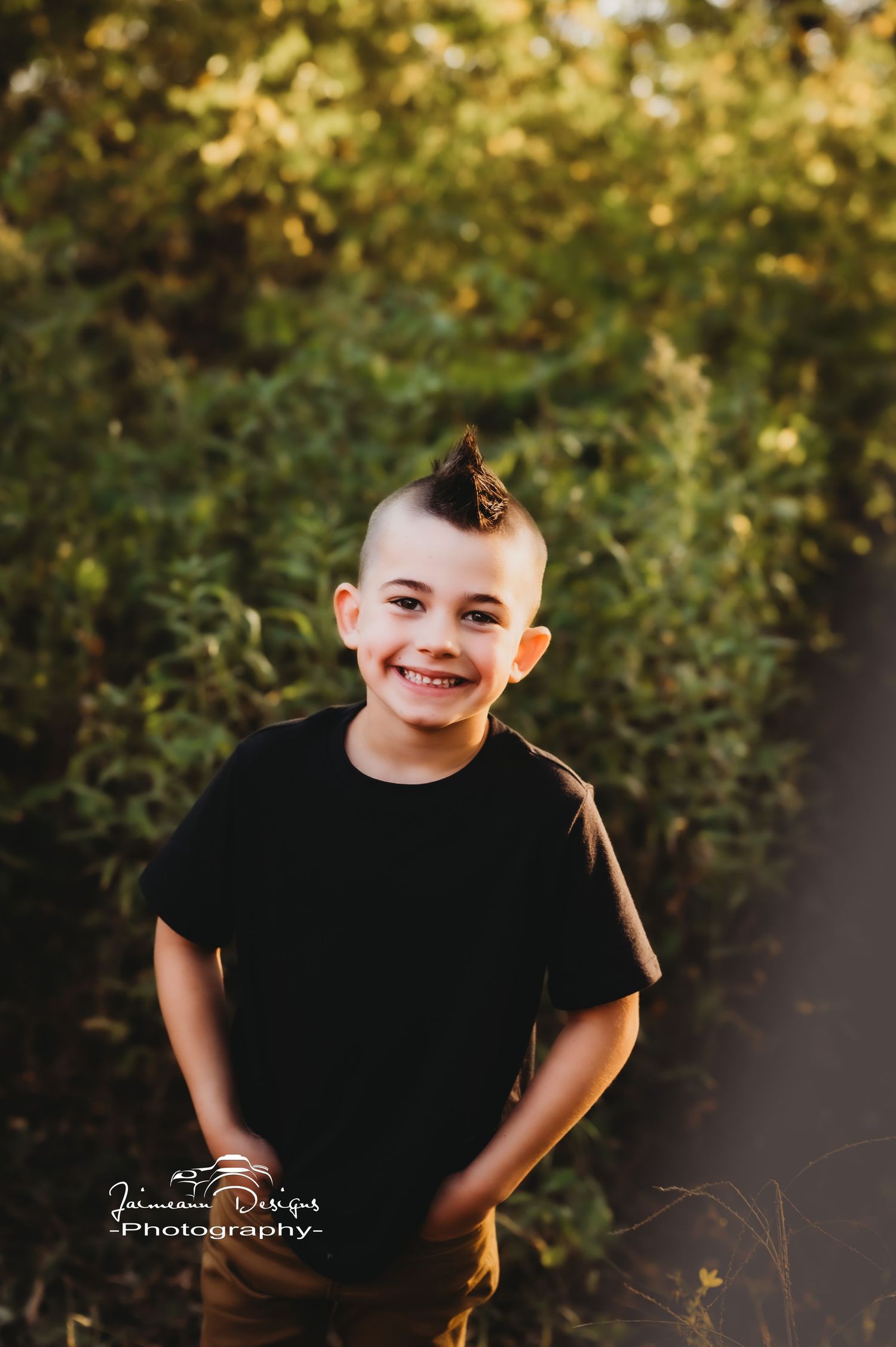 A cheerful outdoor portrait with golden sunlight and green foliage in the background.