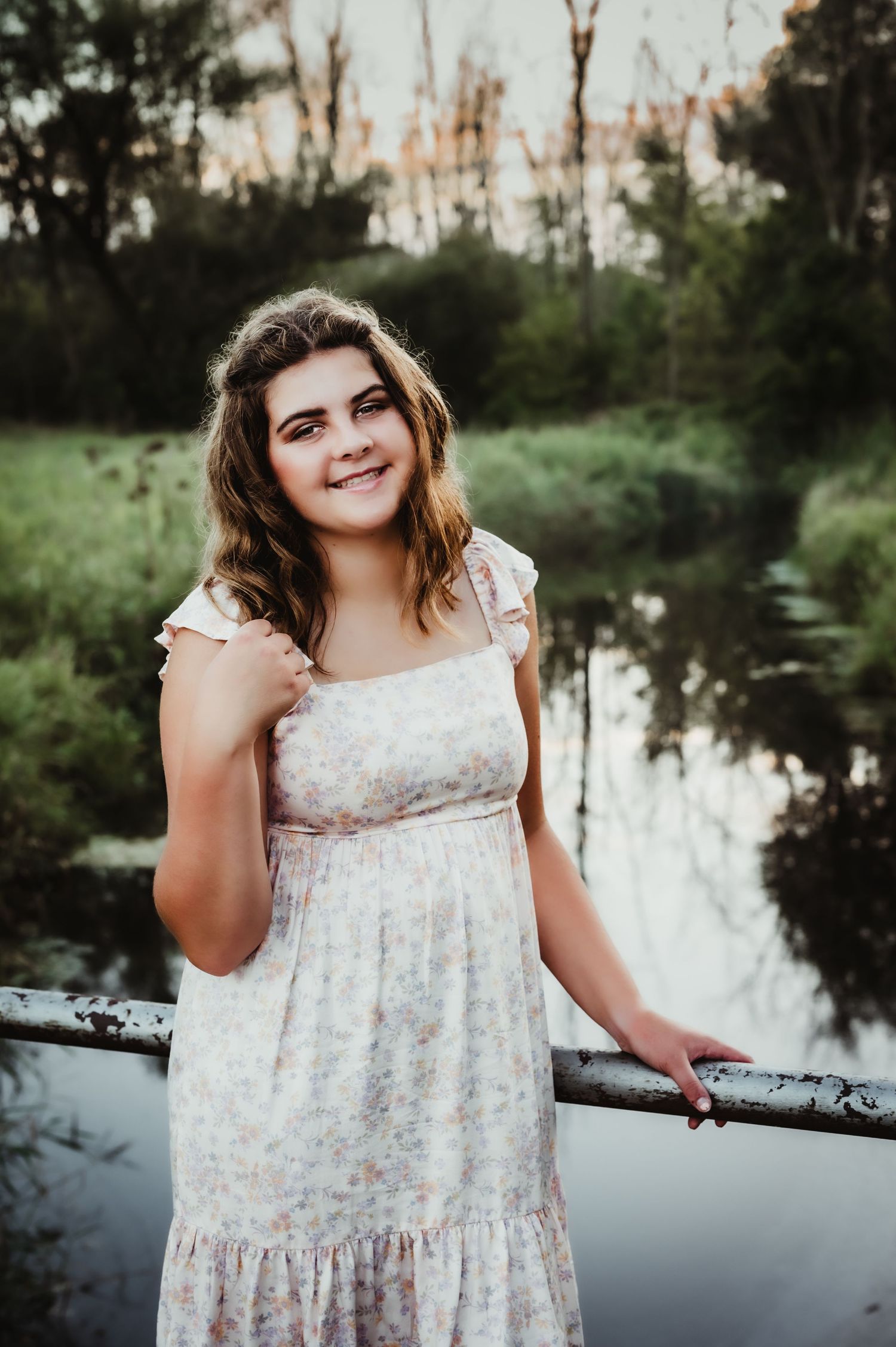 Natural outdoor portrait featuring someone in a vintage-style dress beside a tranquil pond.