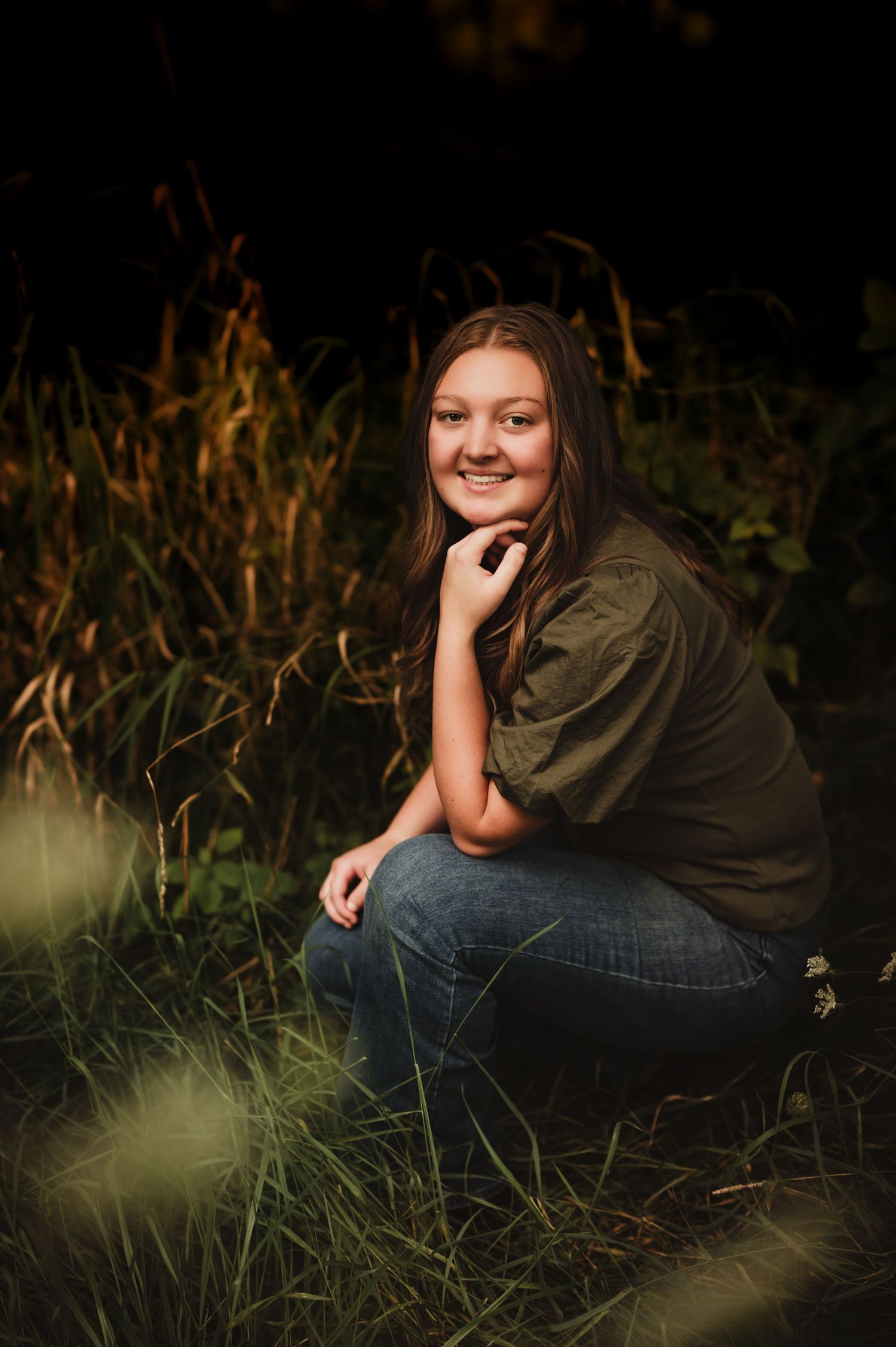 Casual outdoor portrait in olive shirt and jeans among tall grass.