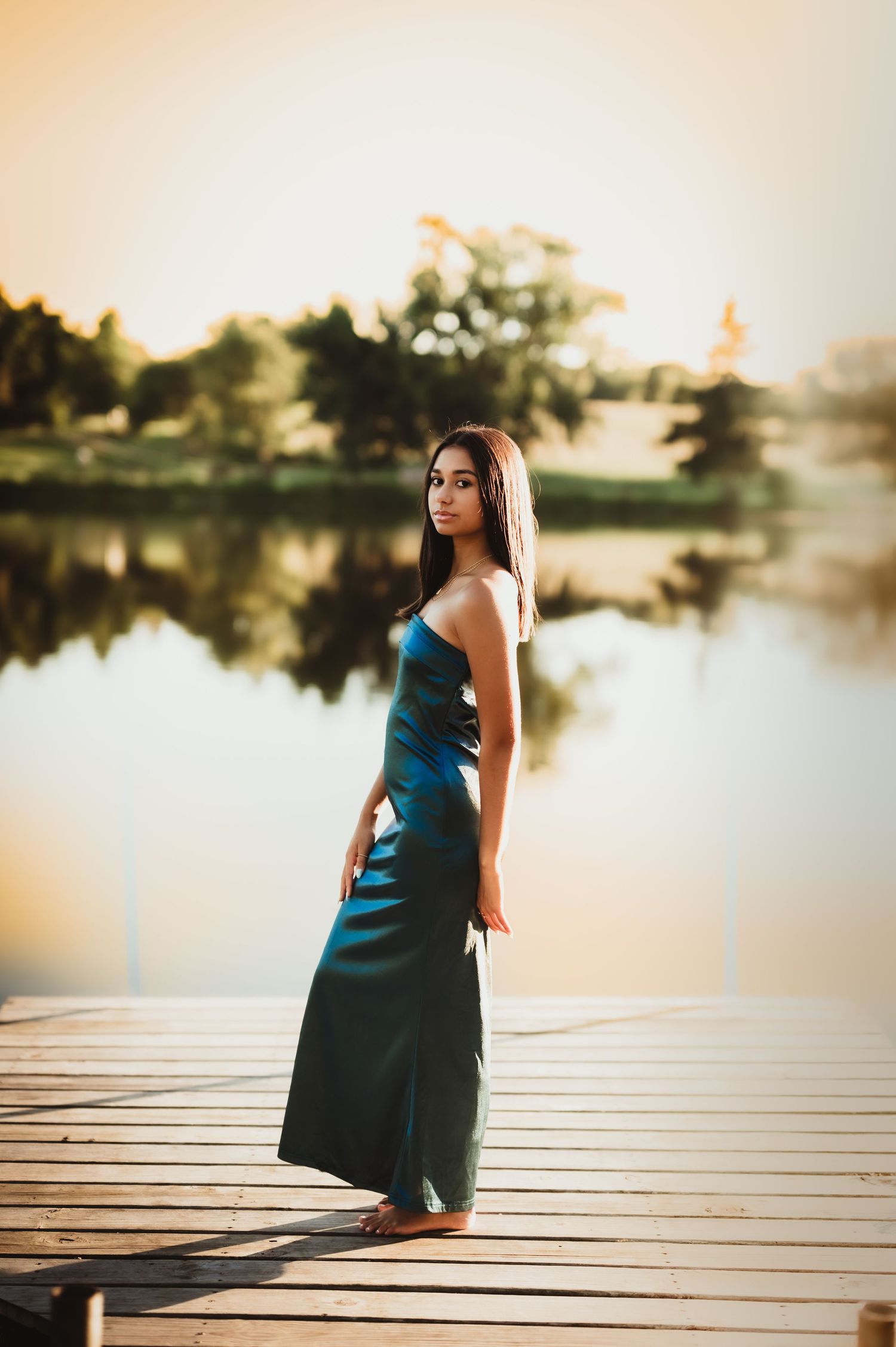 Elegant dress photography on lakeside dock during golden hour.
