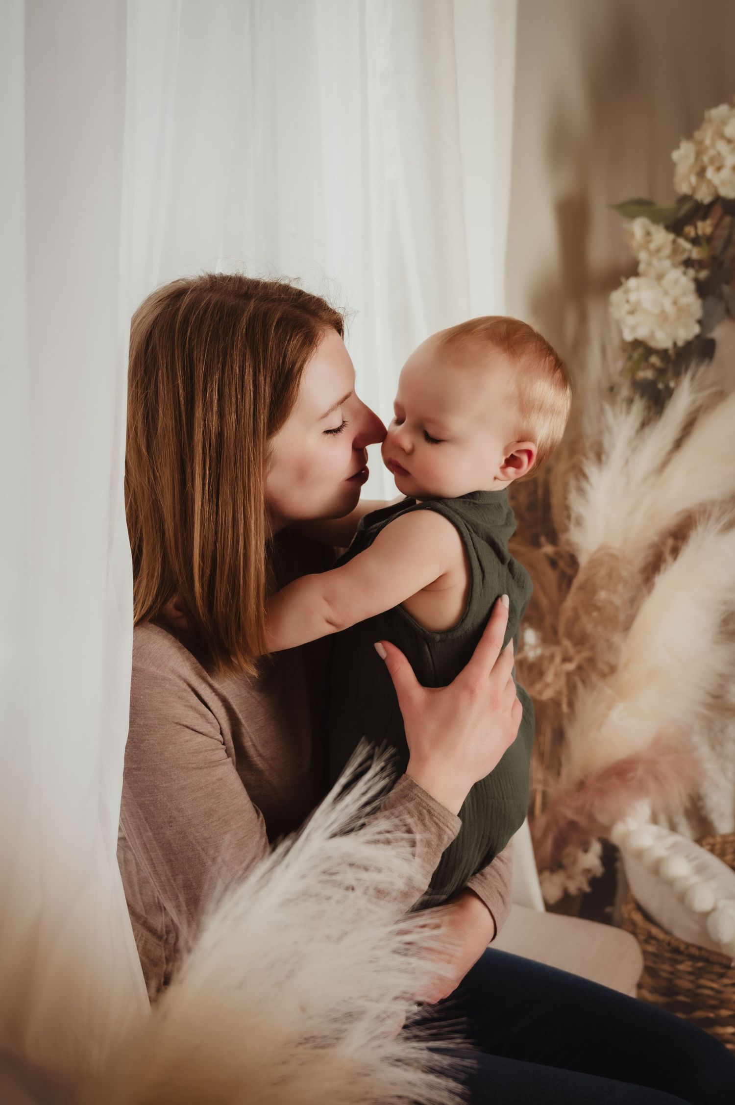 A touching moment between parent and infant captured in a softly lit, neutral-toned nursery setting.