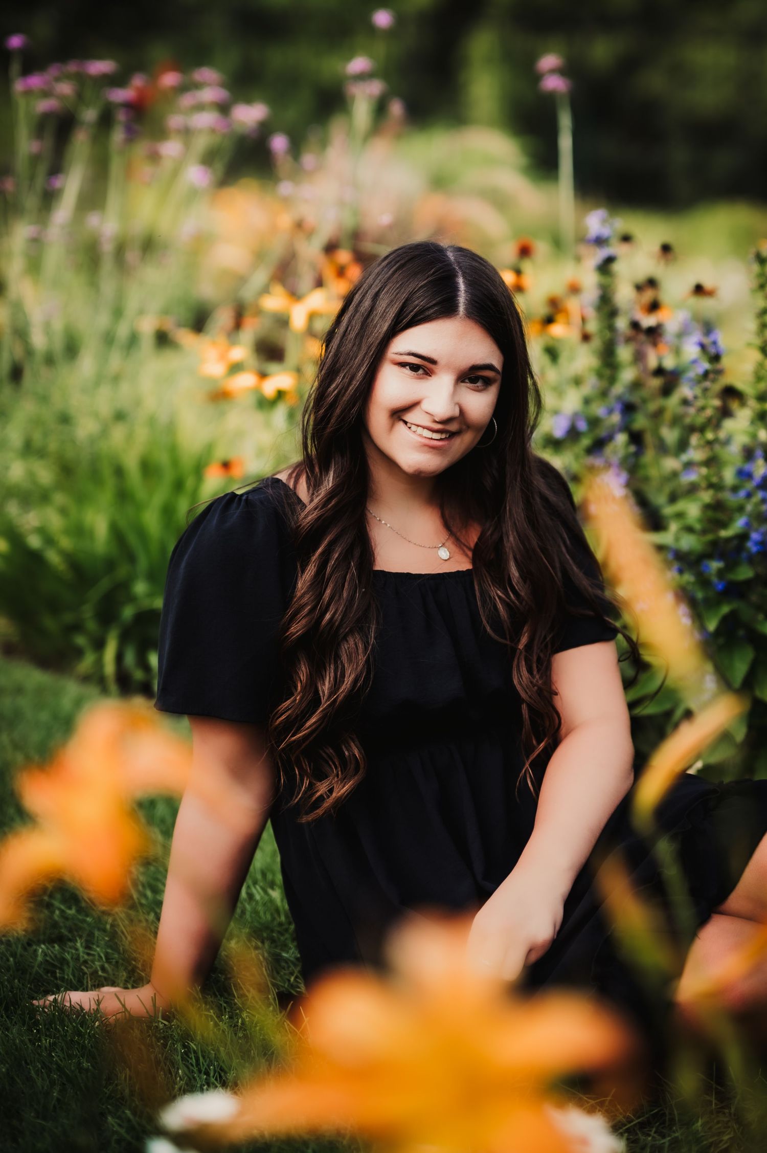 Garden portrait with black dress amid orange flowers and natural greenery.