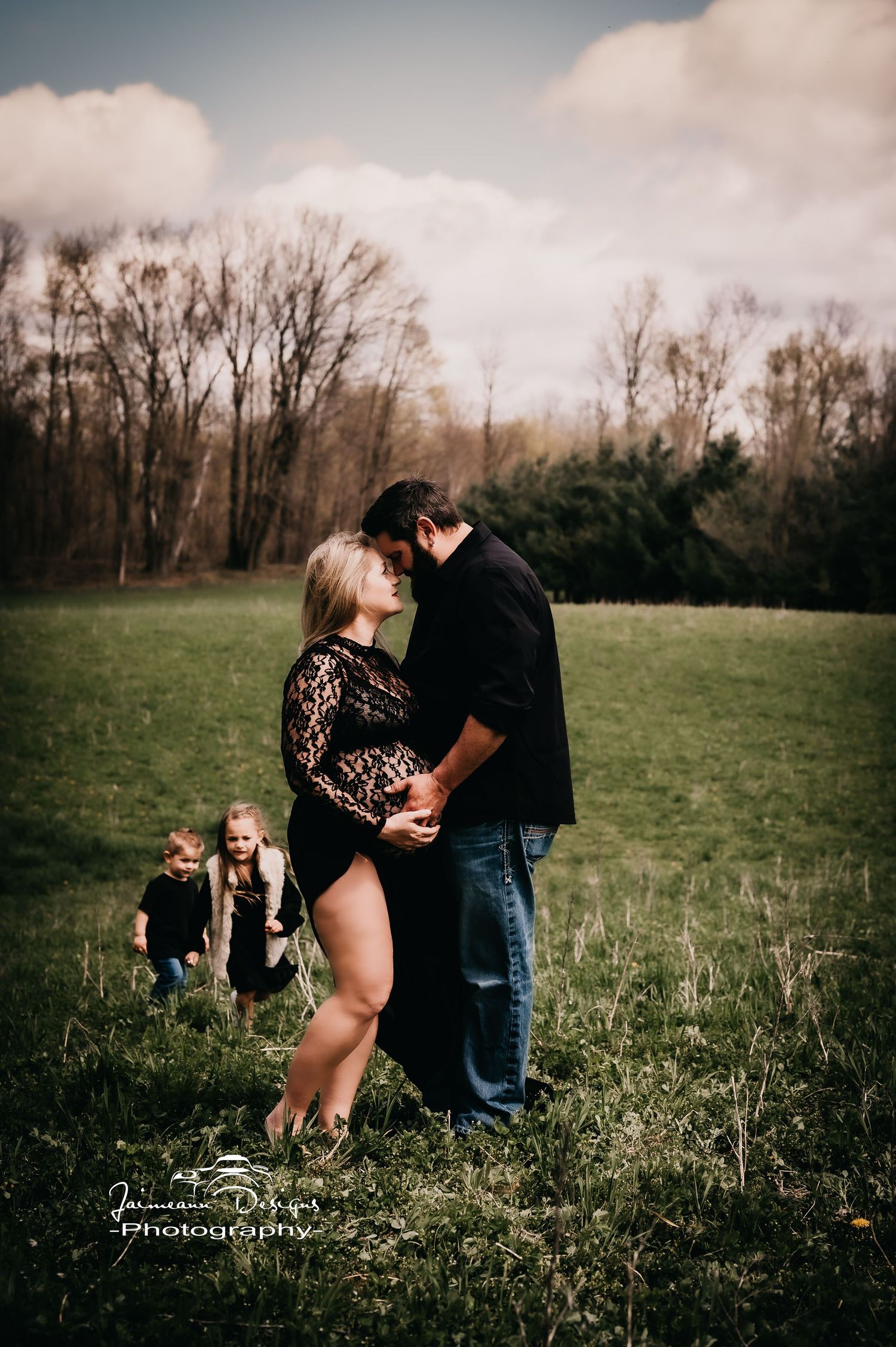 Intimate outdoor maternity photograph in a green field.