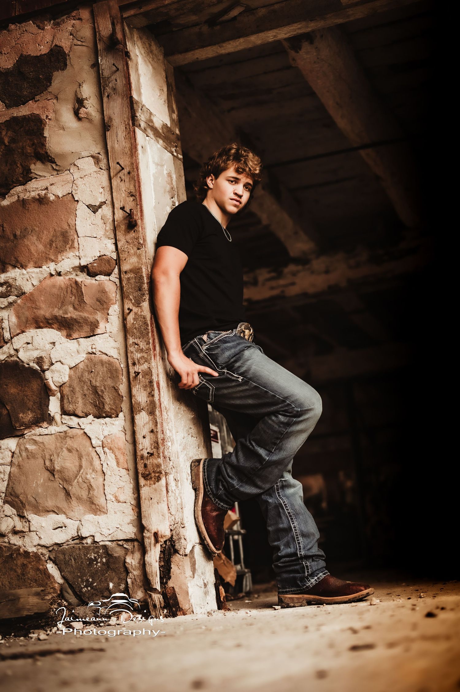 Dramatic portrait against rustic stone wall in dark rustic setting.