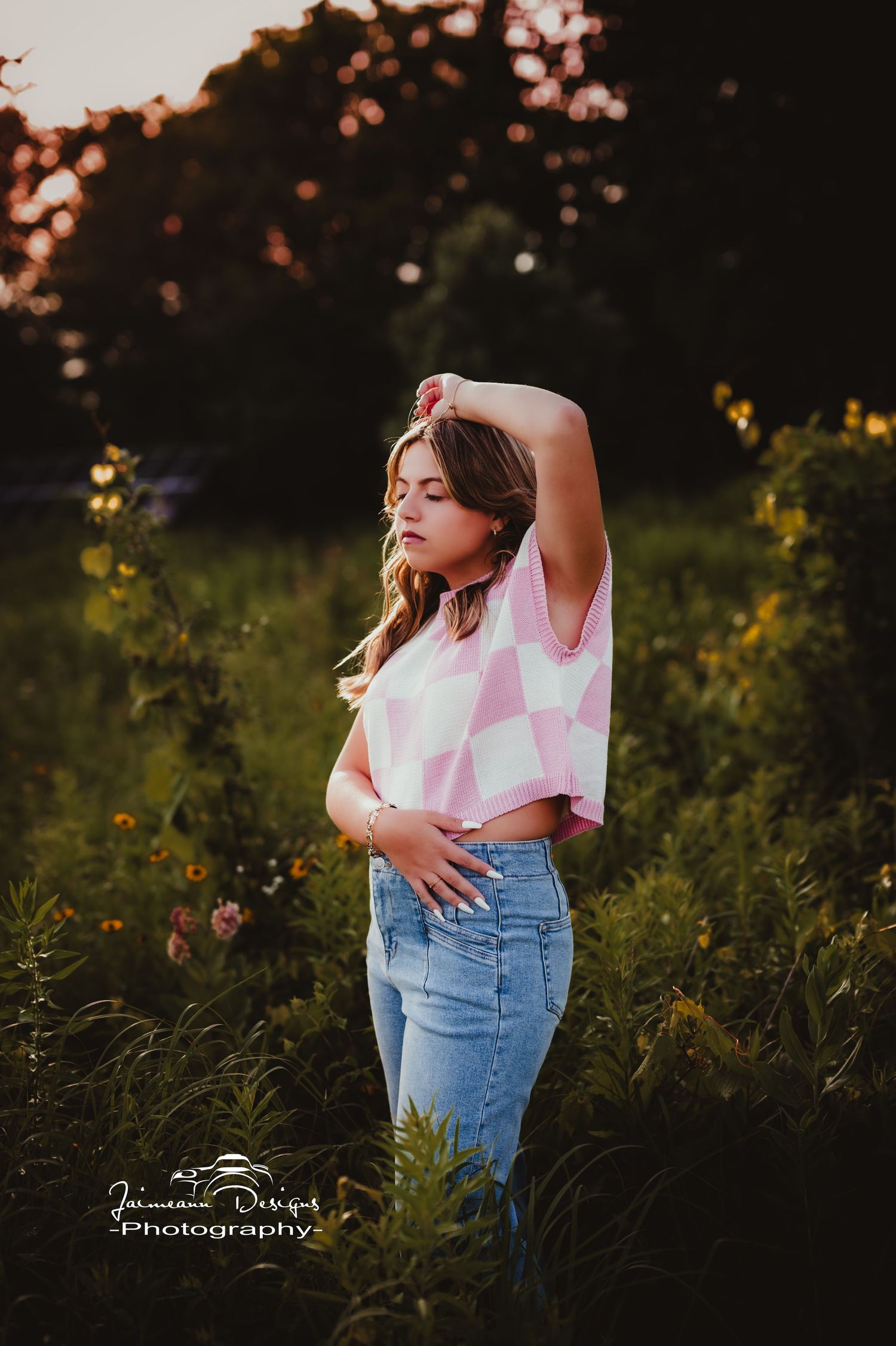 Summer portrait in pink checkered top and jeans against golden sunset lighting.