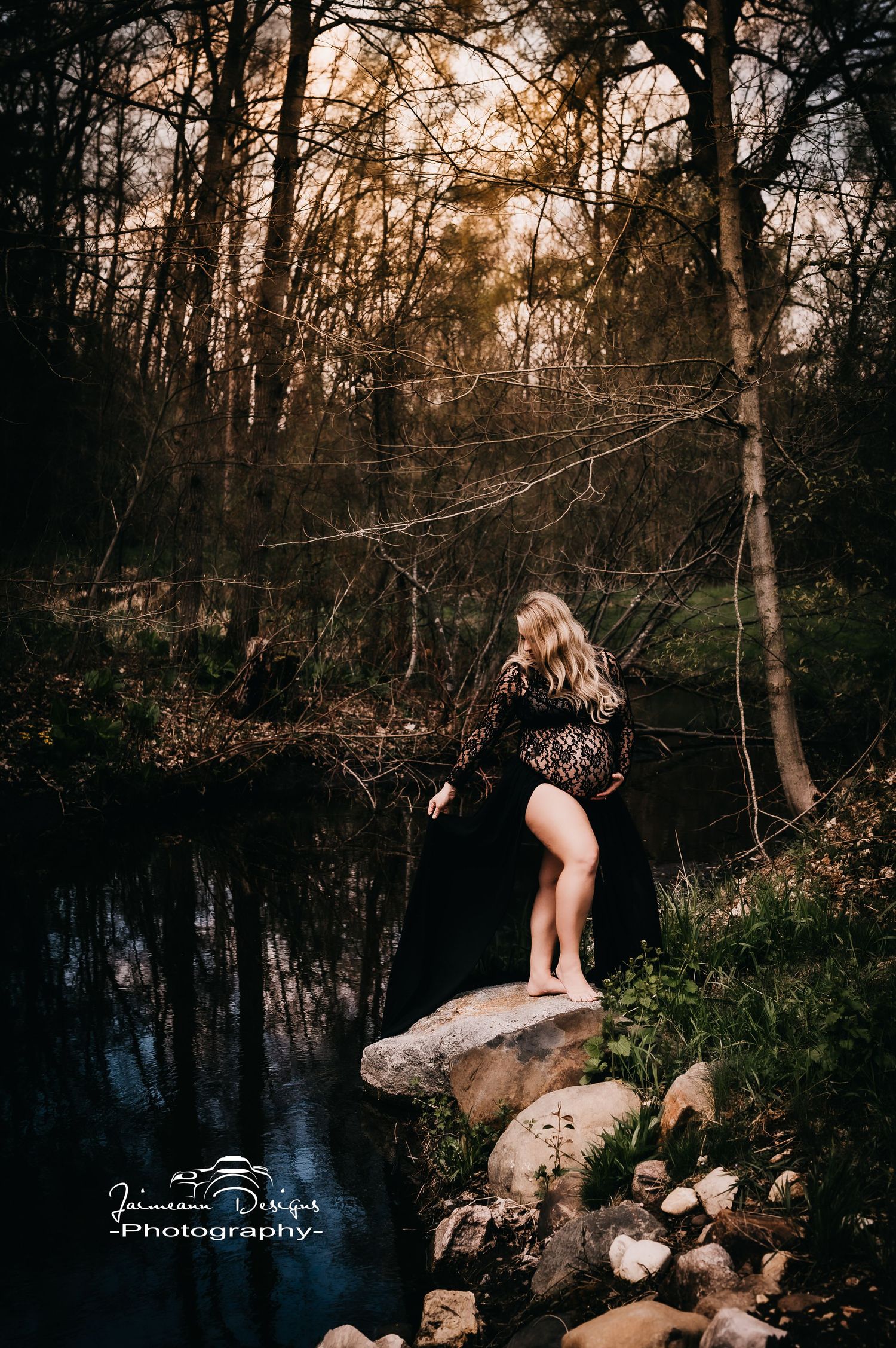 Maternity portrait at sunset by water's edge featuring dramatic black dress.