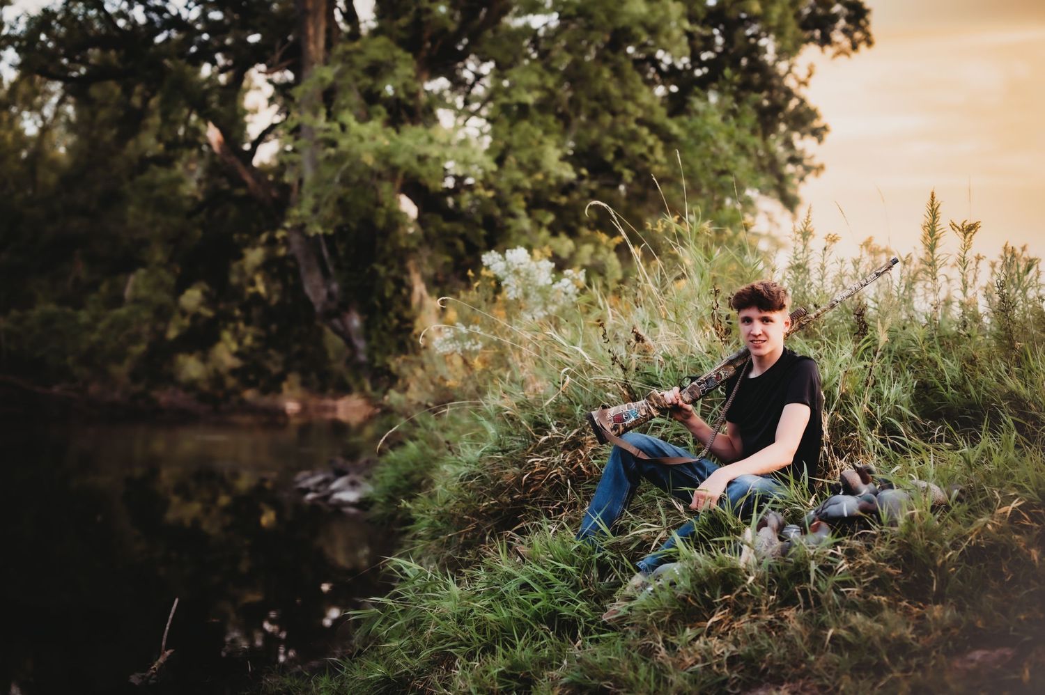 Someone sitting by a pond with fishing gear surrounded by lush greenery.