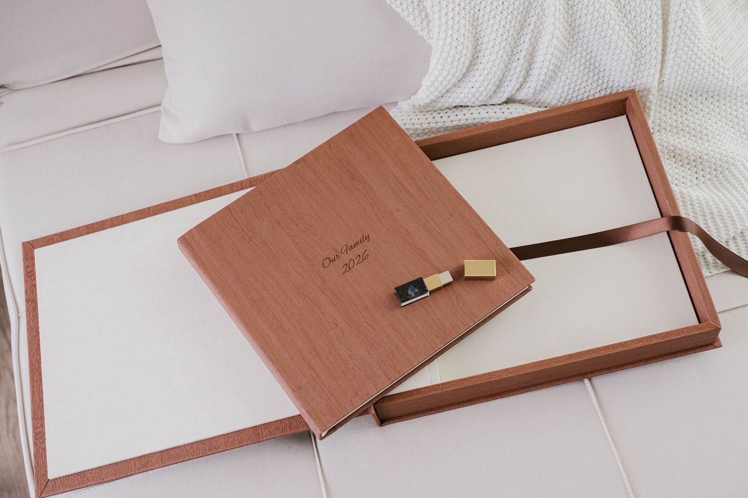 Elegant wooden photo album box with USB drive on white linen surface, perfect for wedding photography packaging.