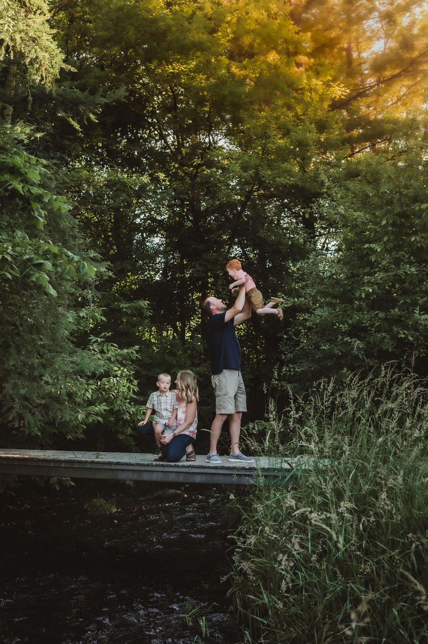 Family spending time together on wooden dock over water during sunset.