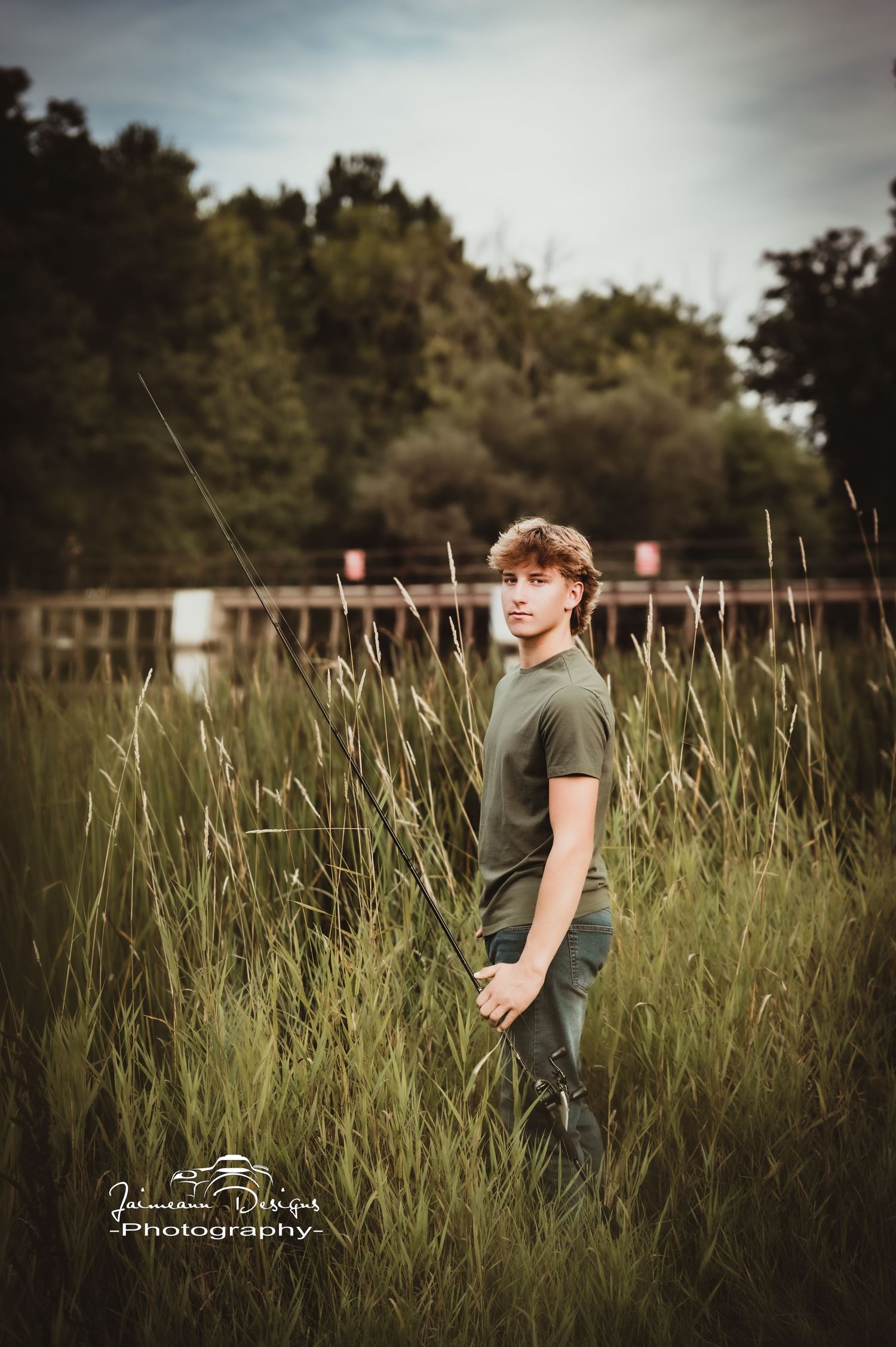 Figure standing in tall grass field at dusk wearing olive green t-shirt.