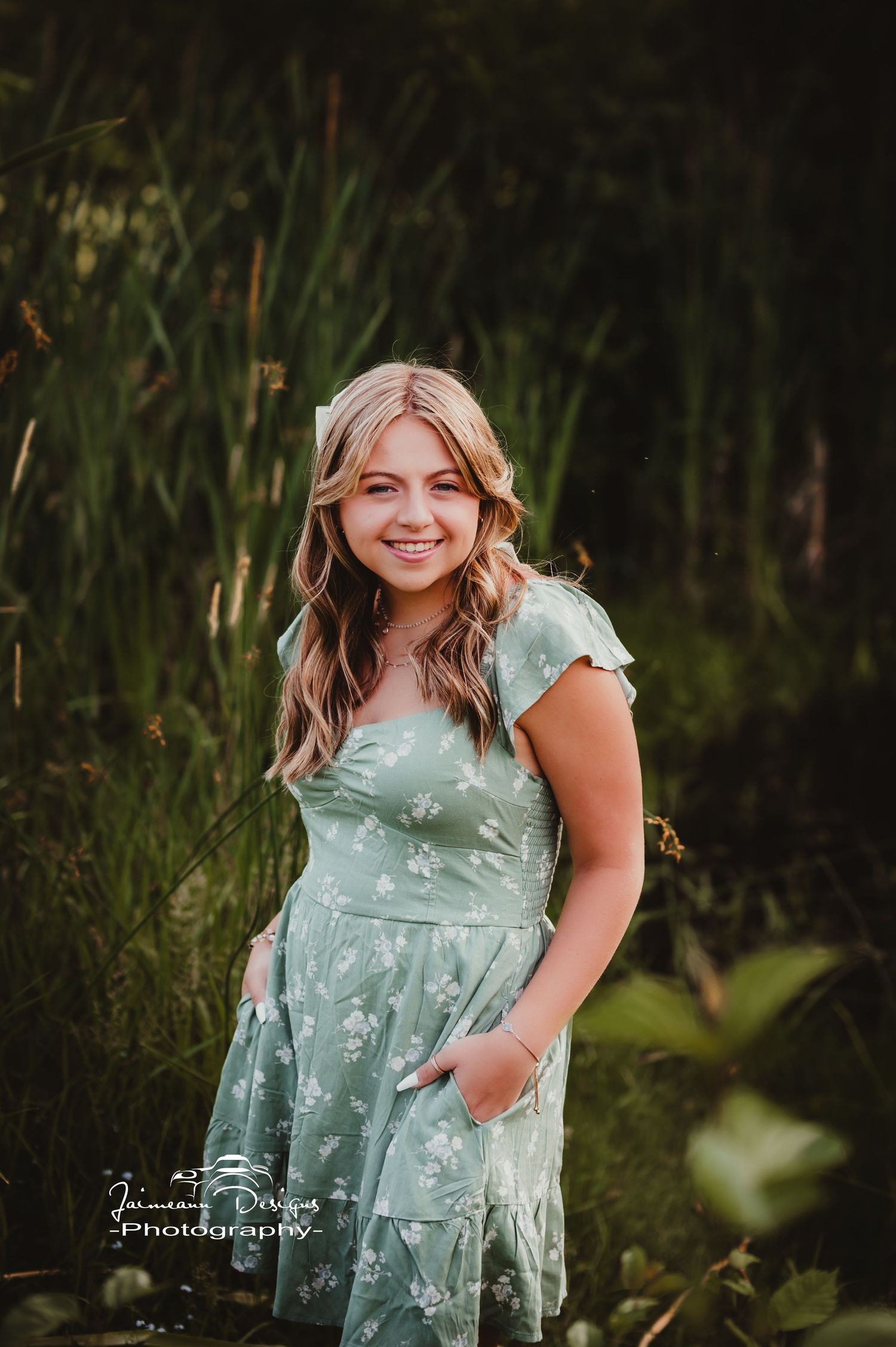 Portrait of someone wearing a mint green floral dress against a natural outdoor background.