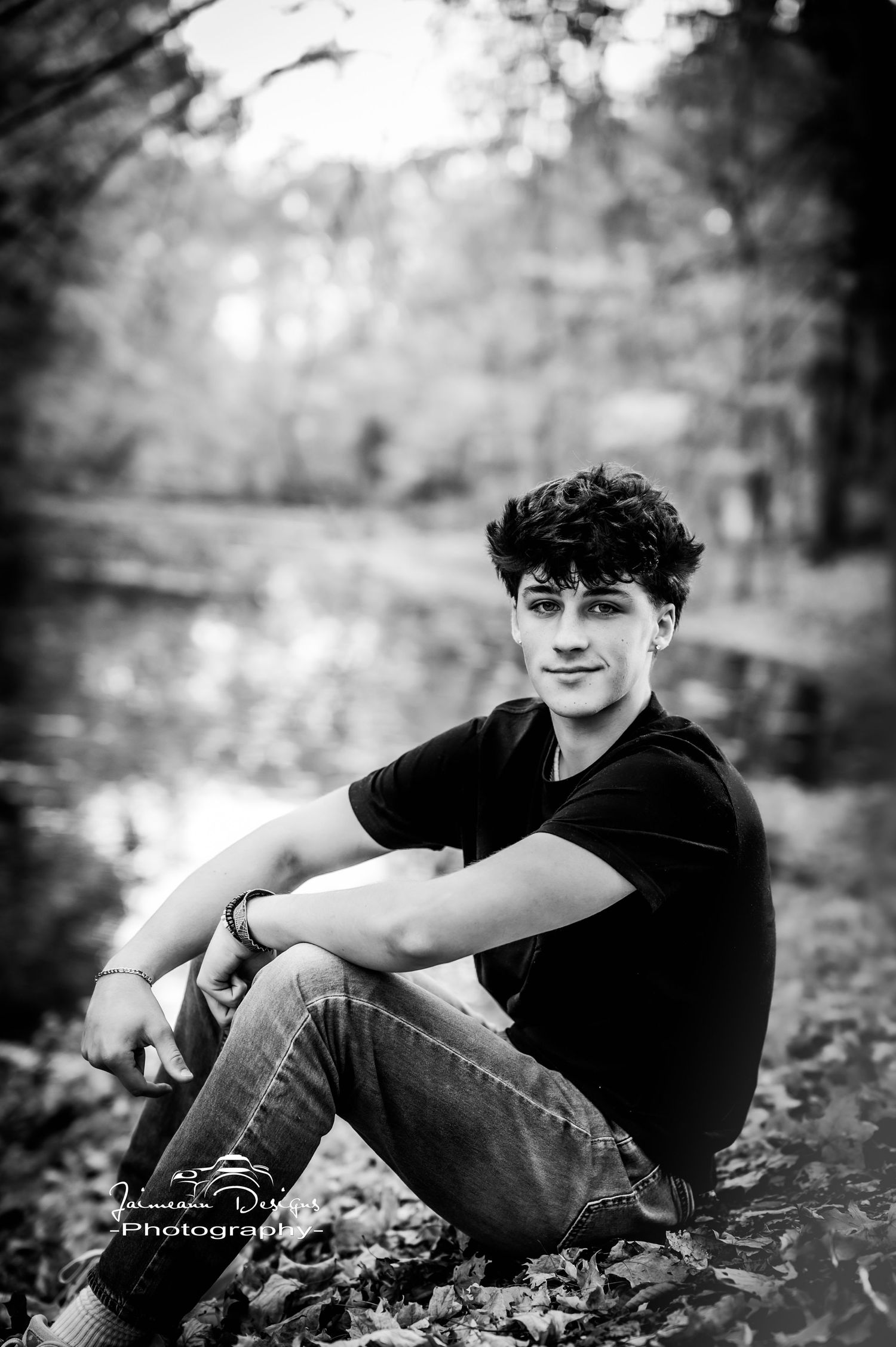 Black and white outdoor portrait sitting among fallen leaves.