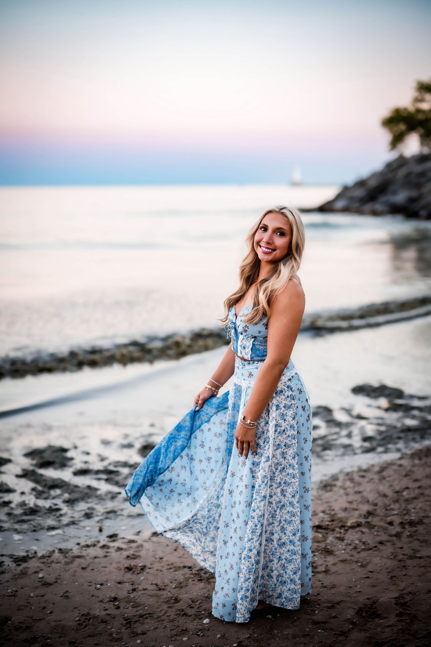 Senior girl posing on the beach at sunset with Lake Michigan behind her