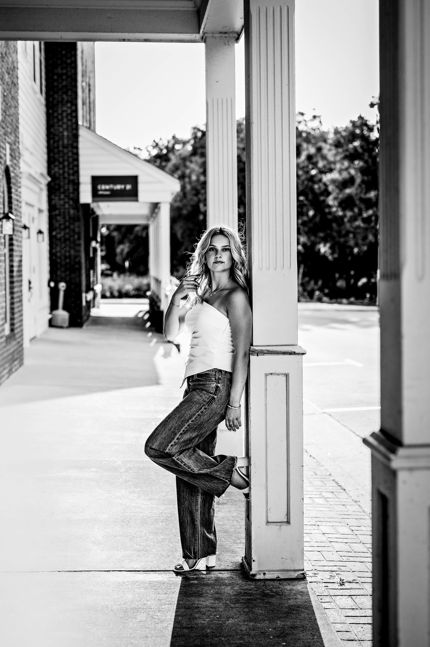 Black and white triptych of a person leaning against white columns in three similar but distinct poses in city of Delafield, WI