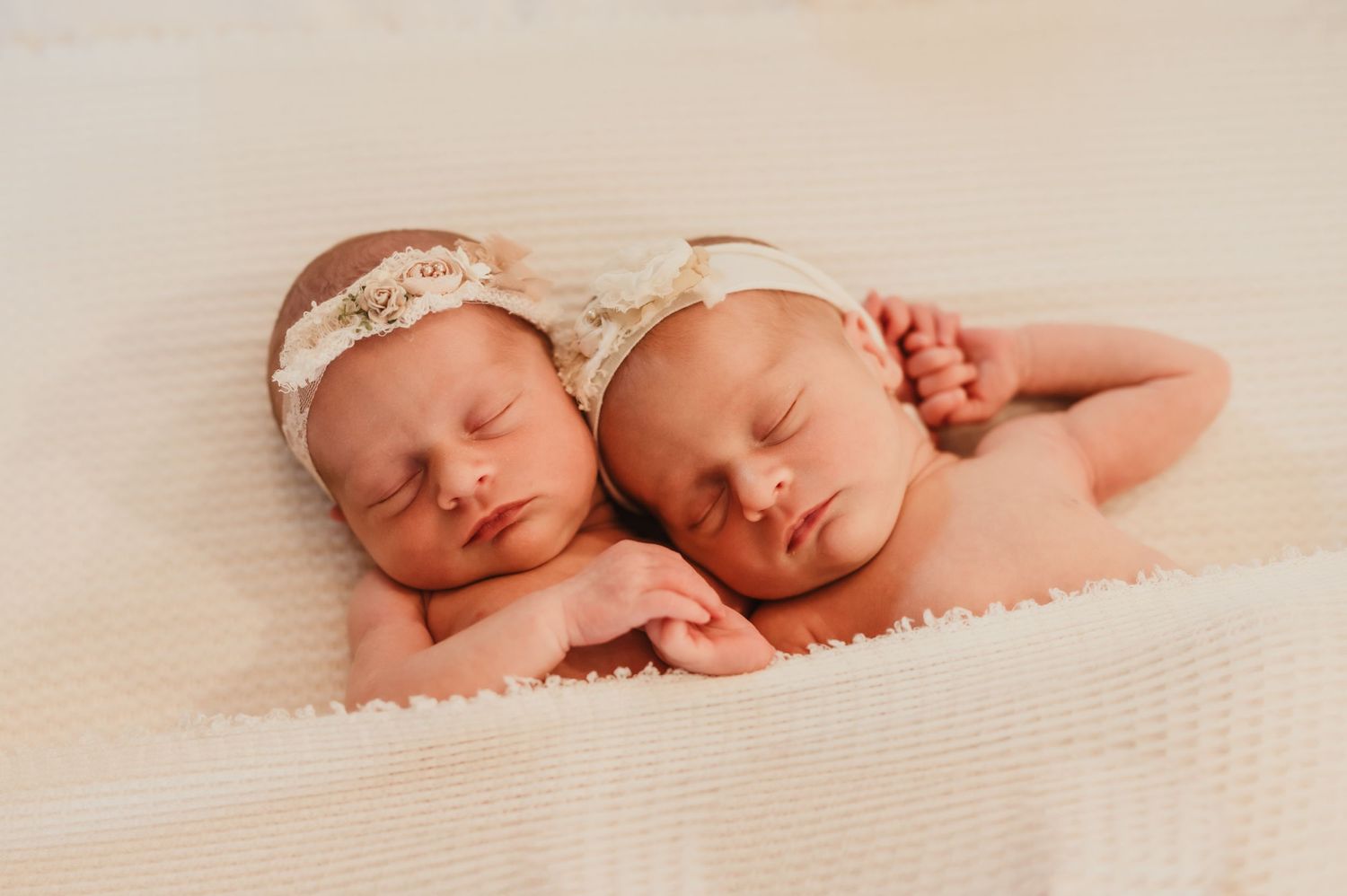 Peaceful sleeping newborn twins in delicate lace headbands rest side by side while the Kewaskum, WI photographer practices trained saftey