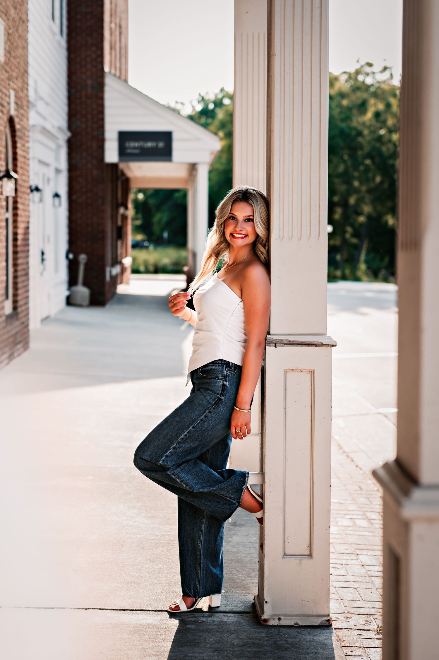 A person in jeans leans against a white column on a porch in a sequence of artistic outdoor photos, Delafield, WI
