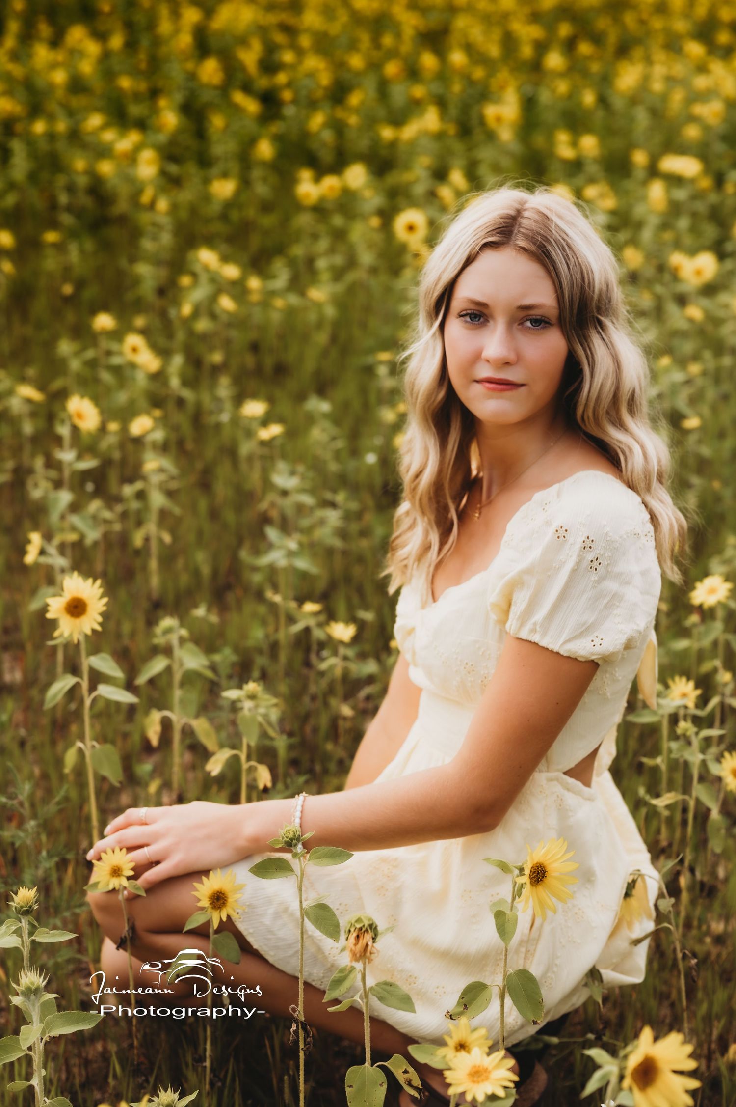 Woman in white dress poses amid vibrant yellow sunflower field.