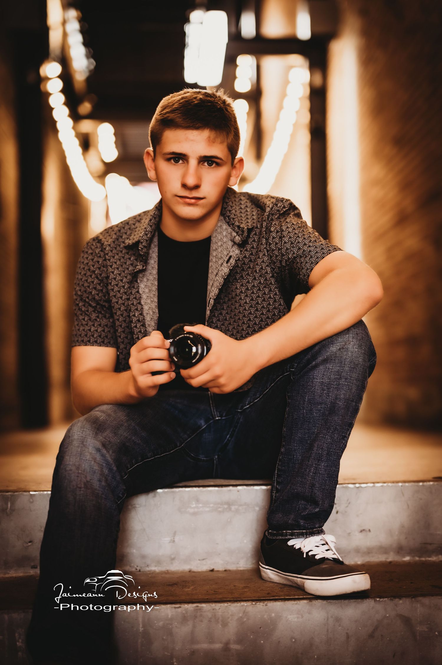 Portrait with camera in warmly lit industrial hallway.