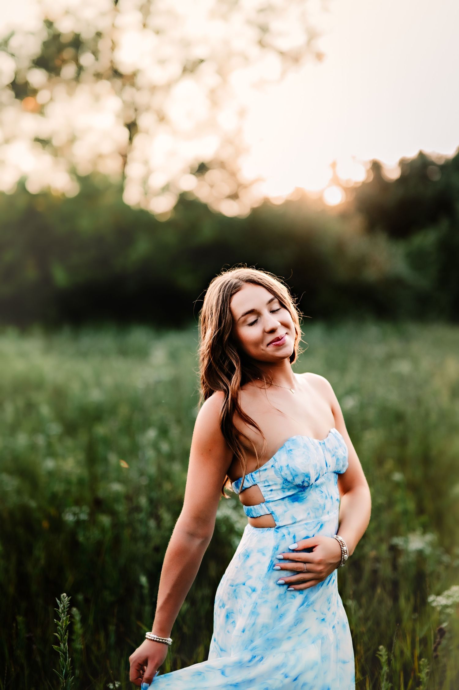 A person in a light blue sundress dances joyfully in a sunlit meadow at golden hour in Kewaskum, WI