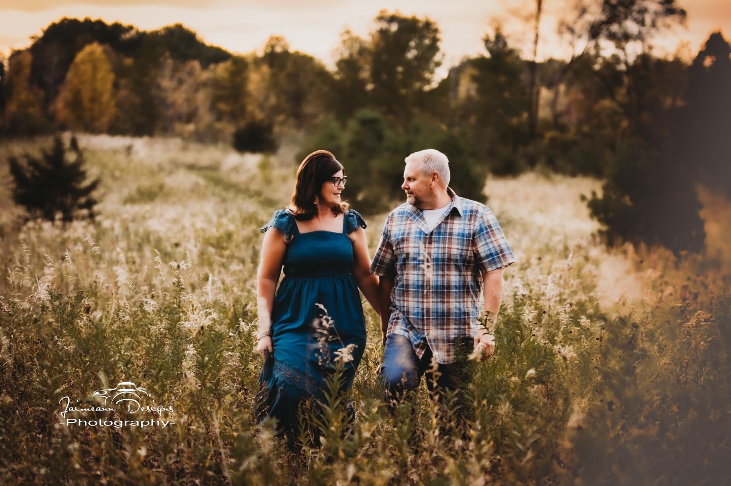 Couple enjoying intimate moment together in tall grass field at sunset.