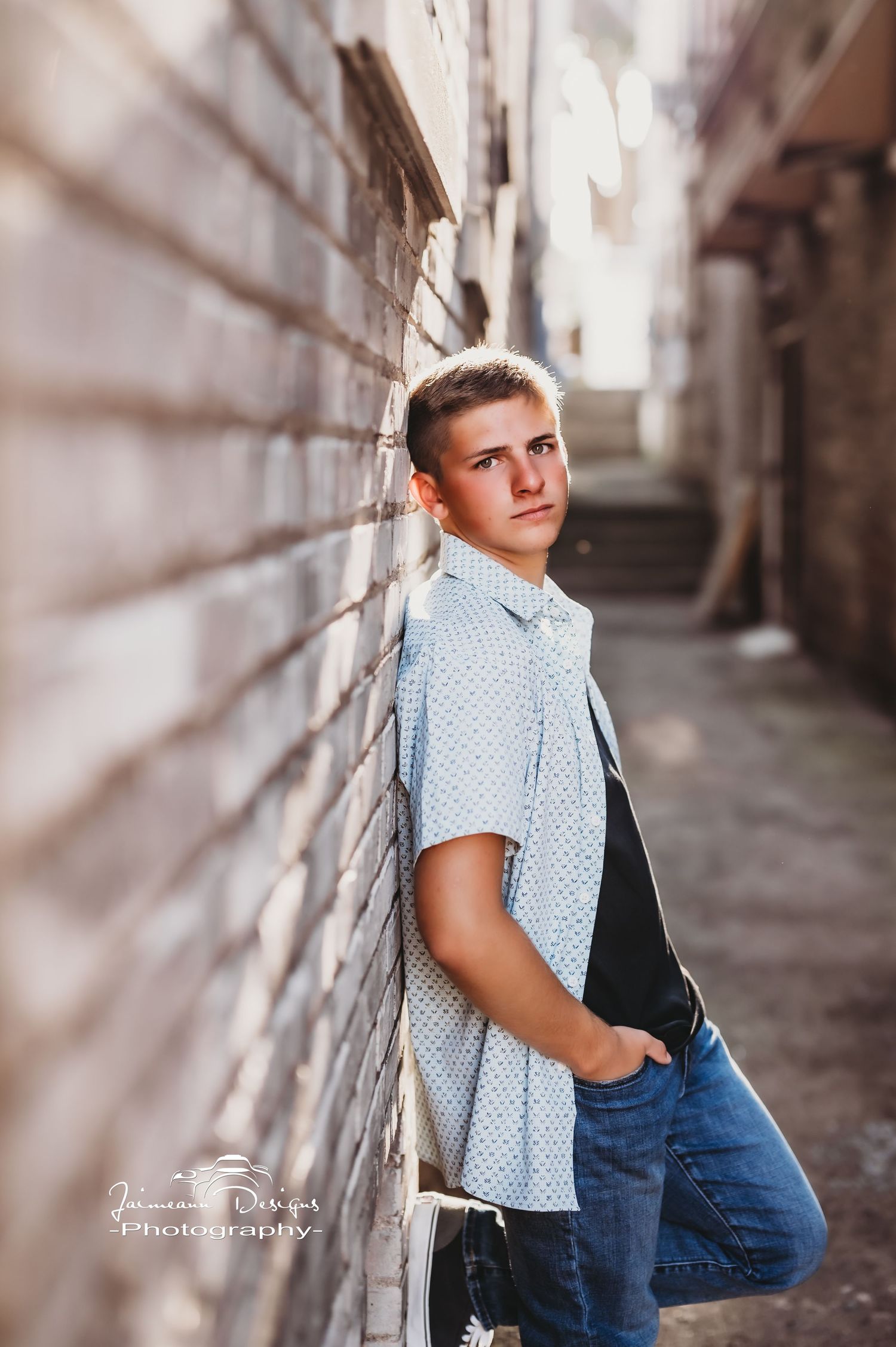 Portrait against brick wall in narrow alleyway with natural lighting.