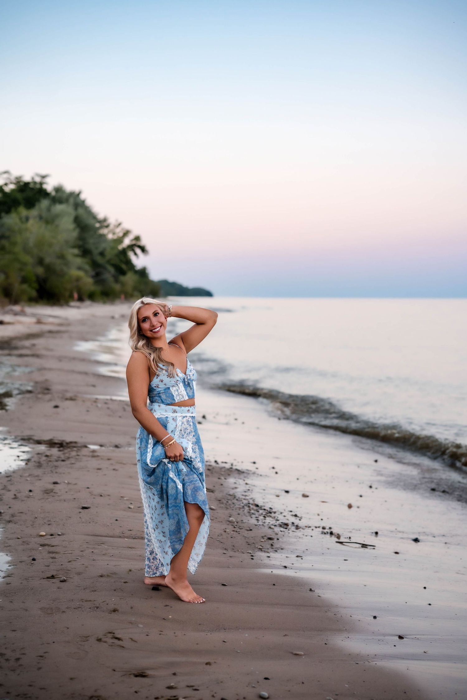 Senior girl smiling with her hand in her hair on a Port Washington beach