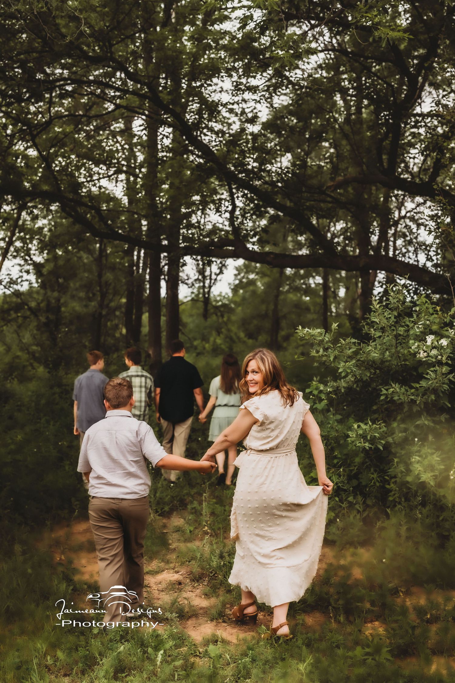 People walking together on a woodland path during a casual outdoor photo session.