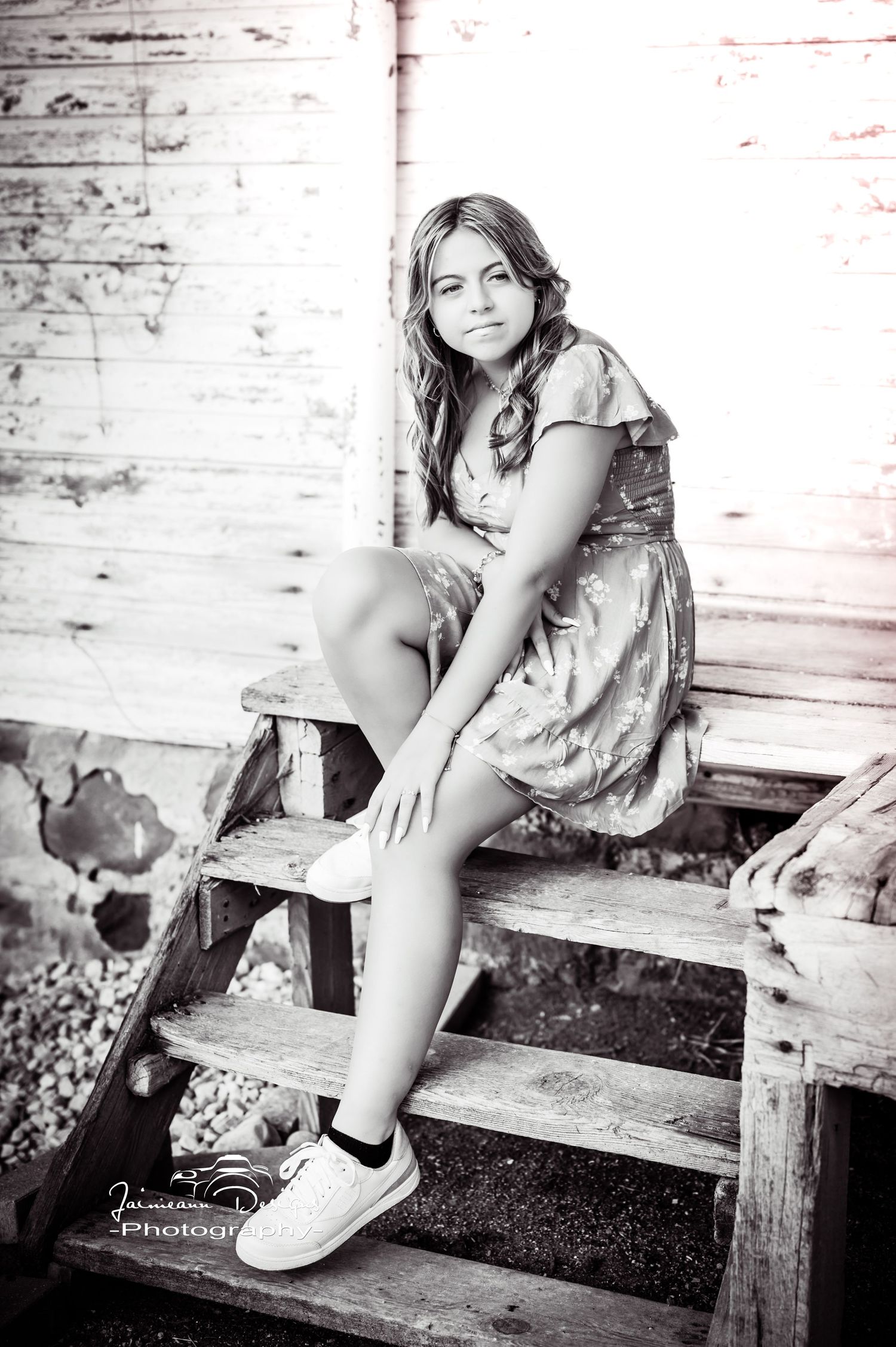 A vintage-style black and white portrait on wooden steps wearing white sneakers.