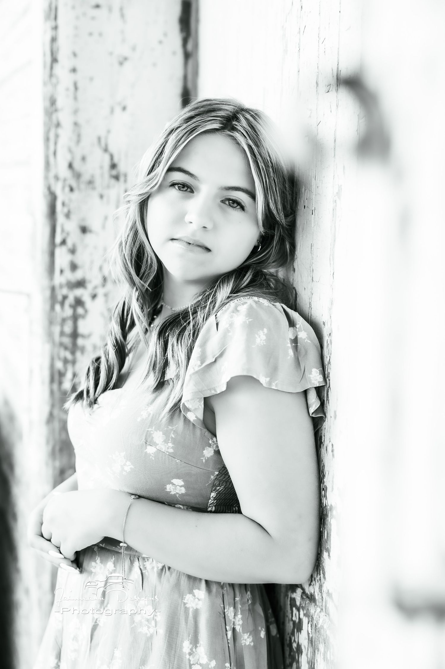 A black and white portrait with soft lighting against a weathered white wall.