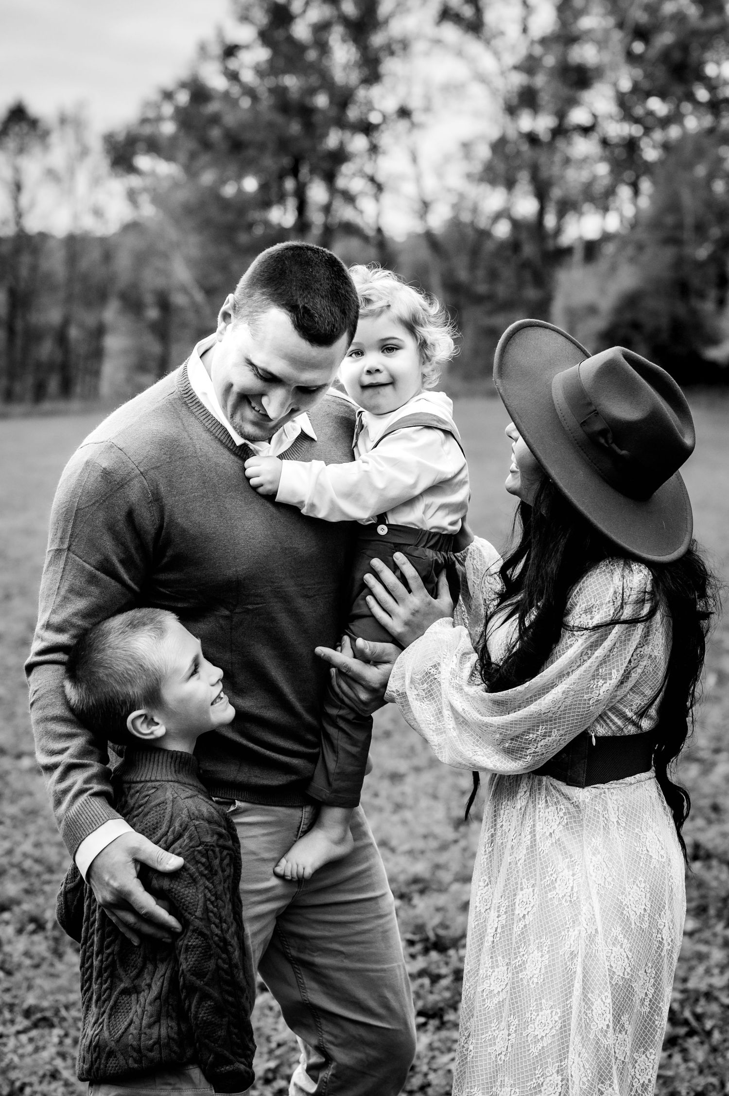 Series of black and white photos capturing joyful family interactions in a natural setting.