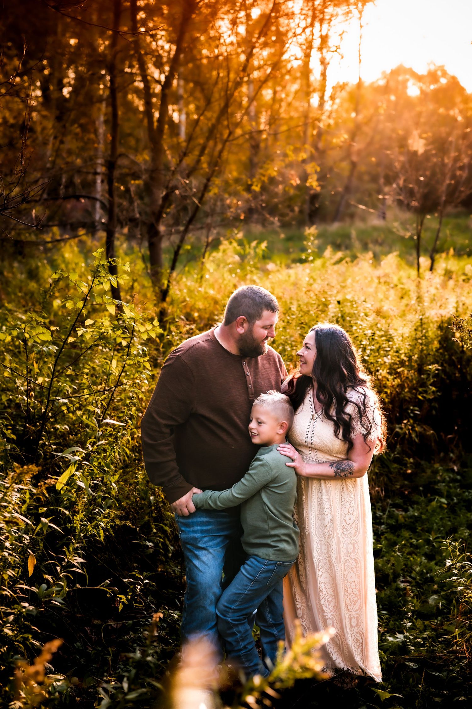 A family shares a tender moment together in a sunlit forest clearing during golden hour. near Milwaukee, WI