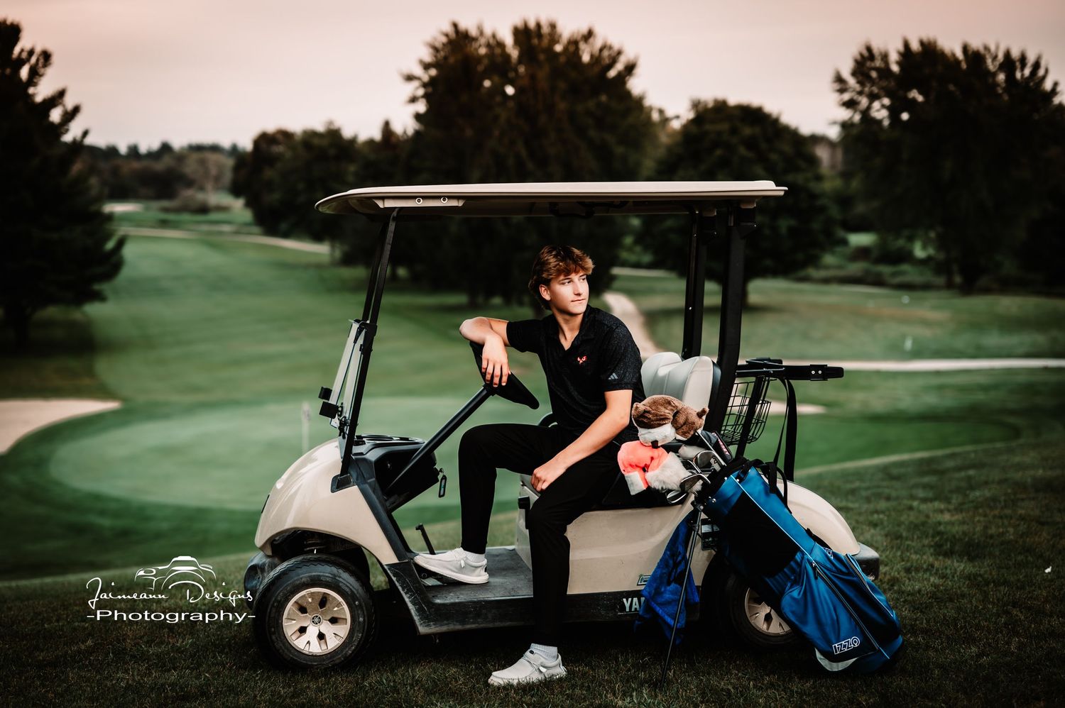 Person on golf cart at sunset on golf course.