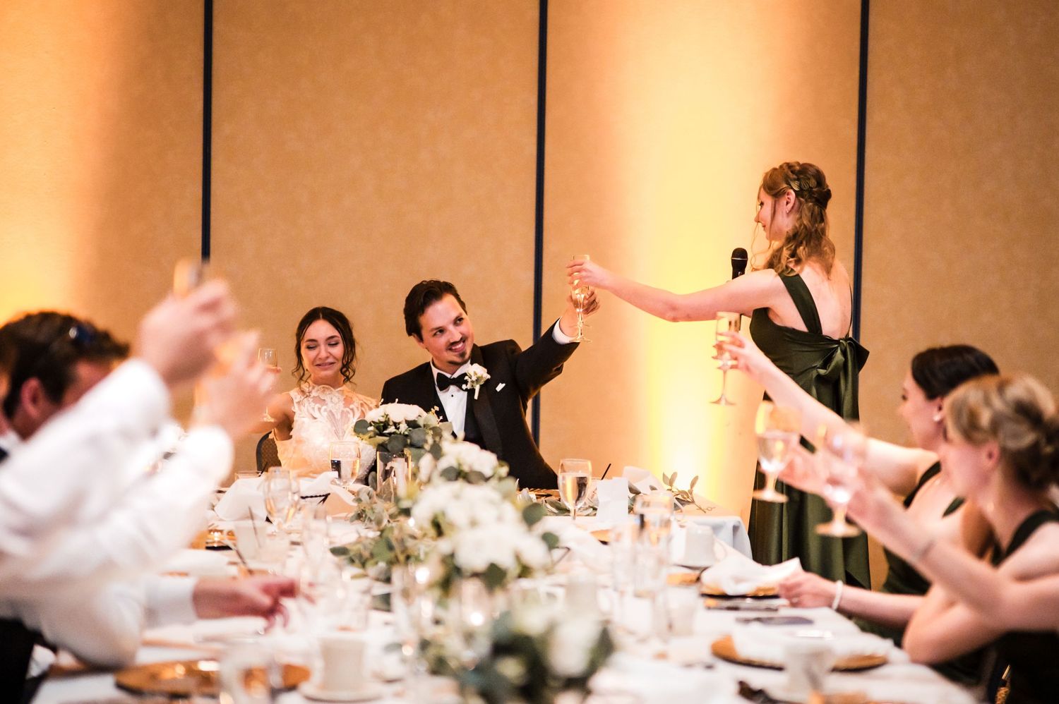 Wedding reception table settings with warm lighting and guests enjoying the celebration.