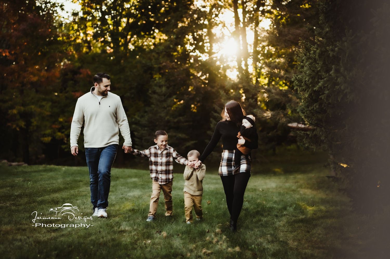 A family walks together during golden hour in a park setting.