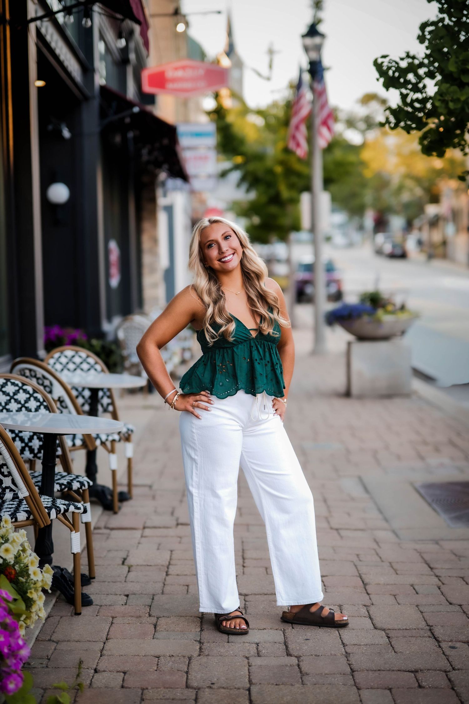 Senior girl in a green top and white pants on a downtown Port Washington sidewalk