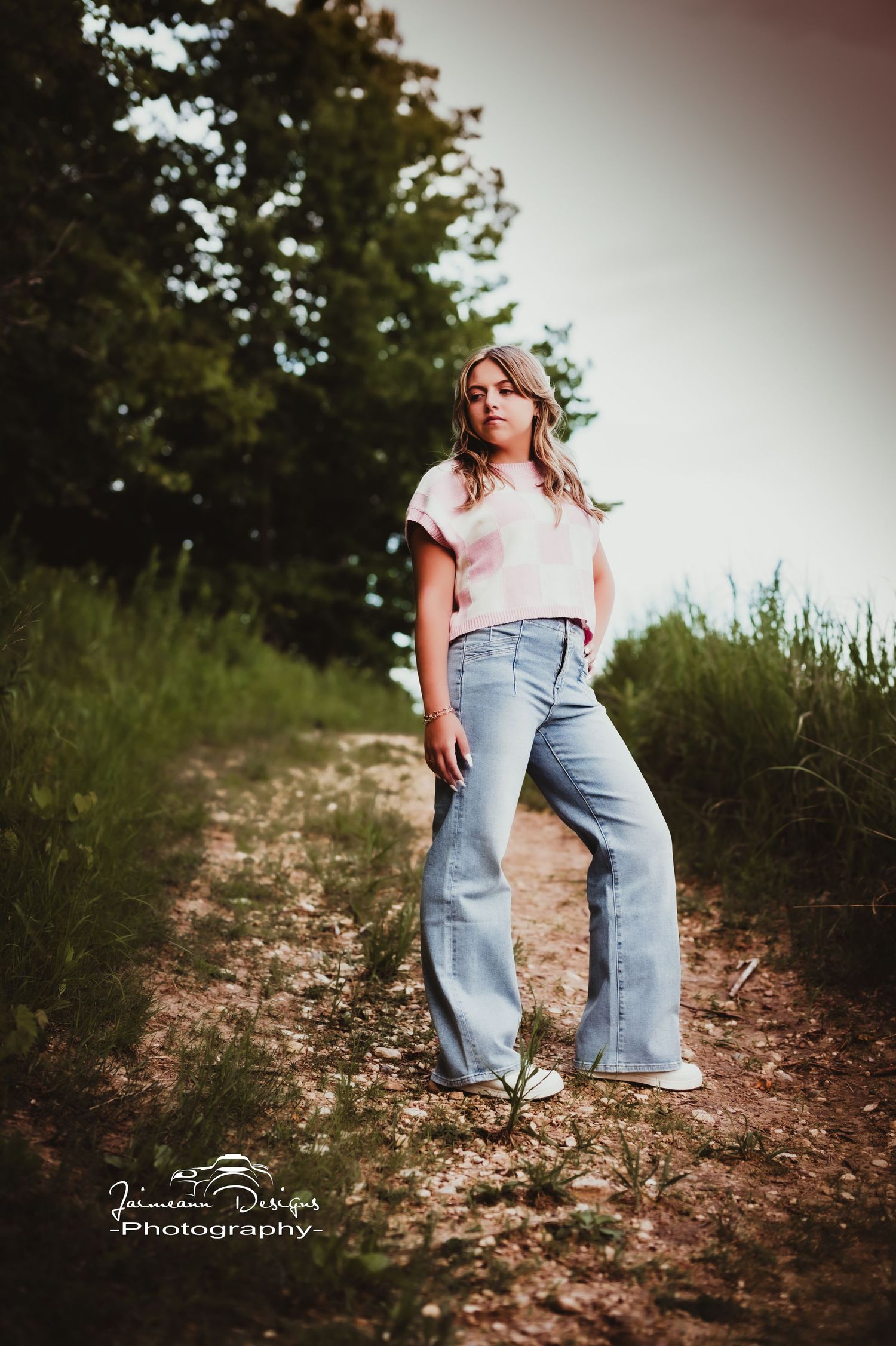 Fashion pose on rustic trail wearing wide-leg denim and casual top.