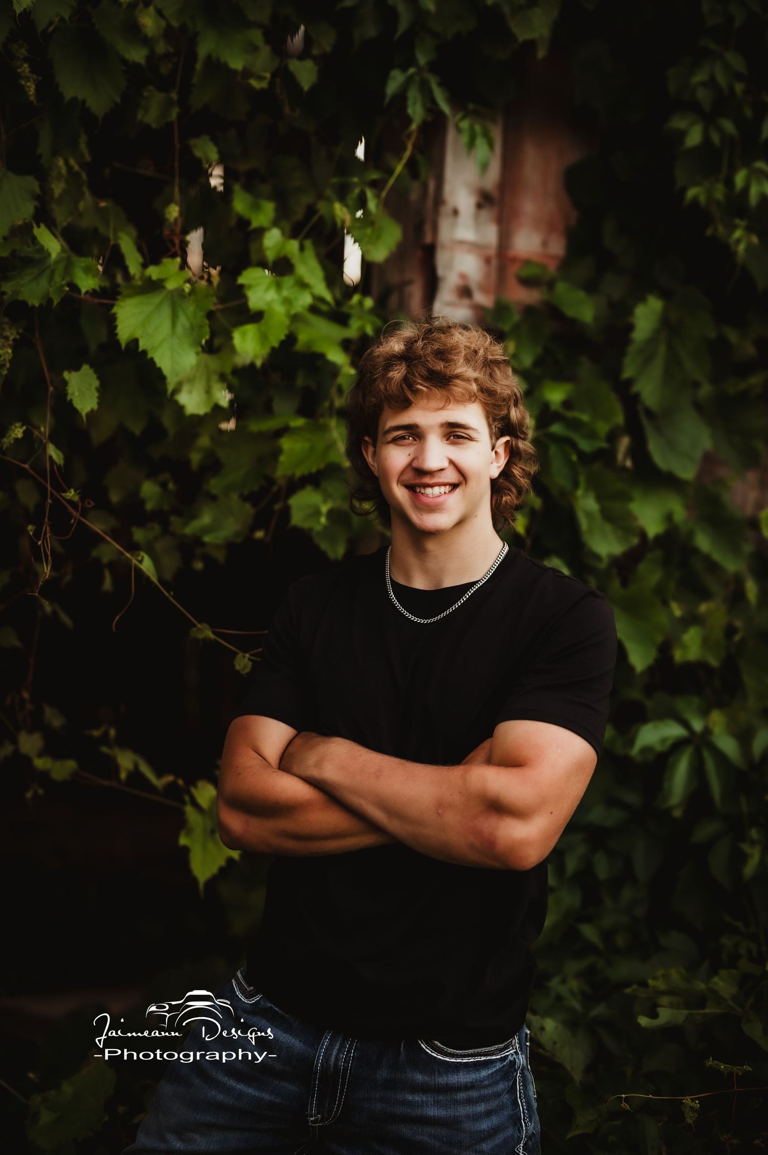 Casual outdoor portrait against green vine-covered wall.