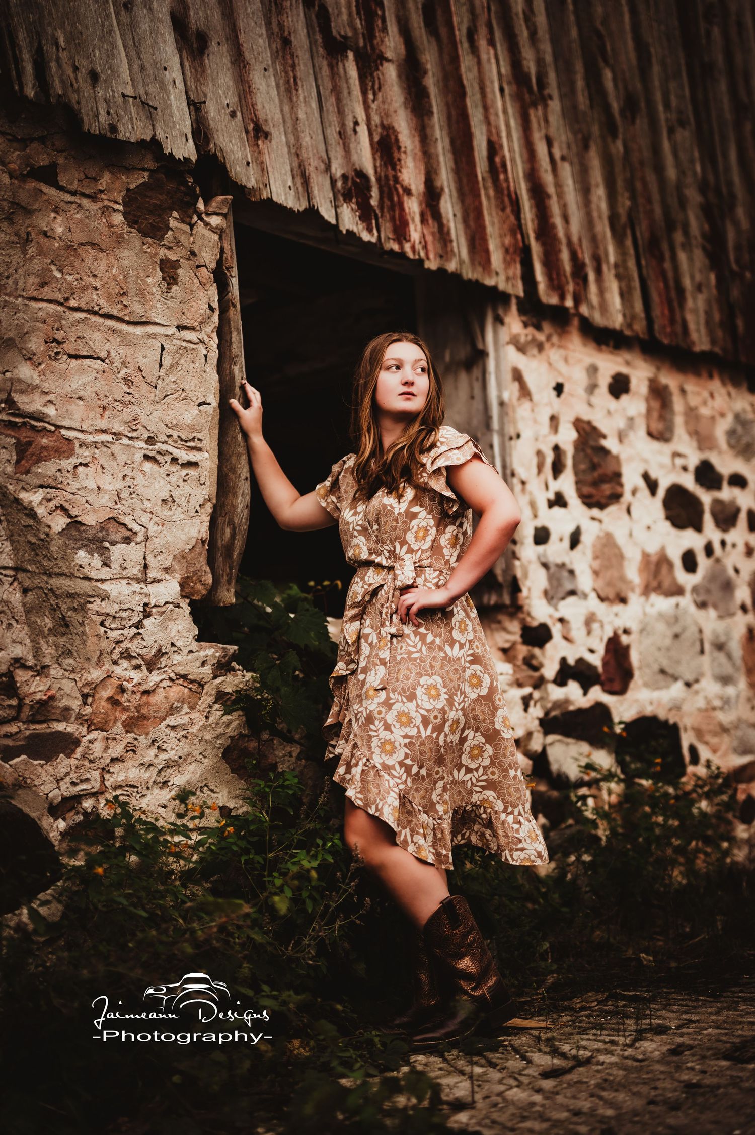 A floral dress complements the rustic stone wall backdrop in this artistic outdoor portrait.