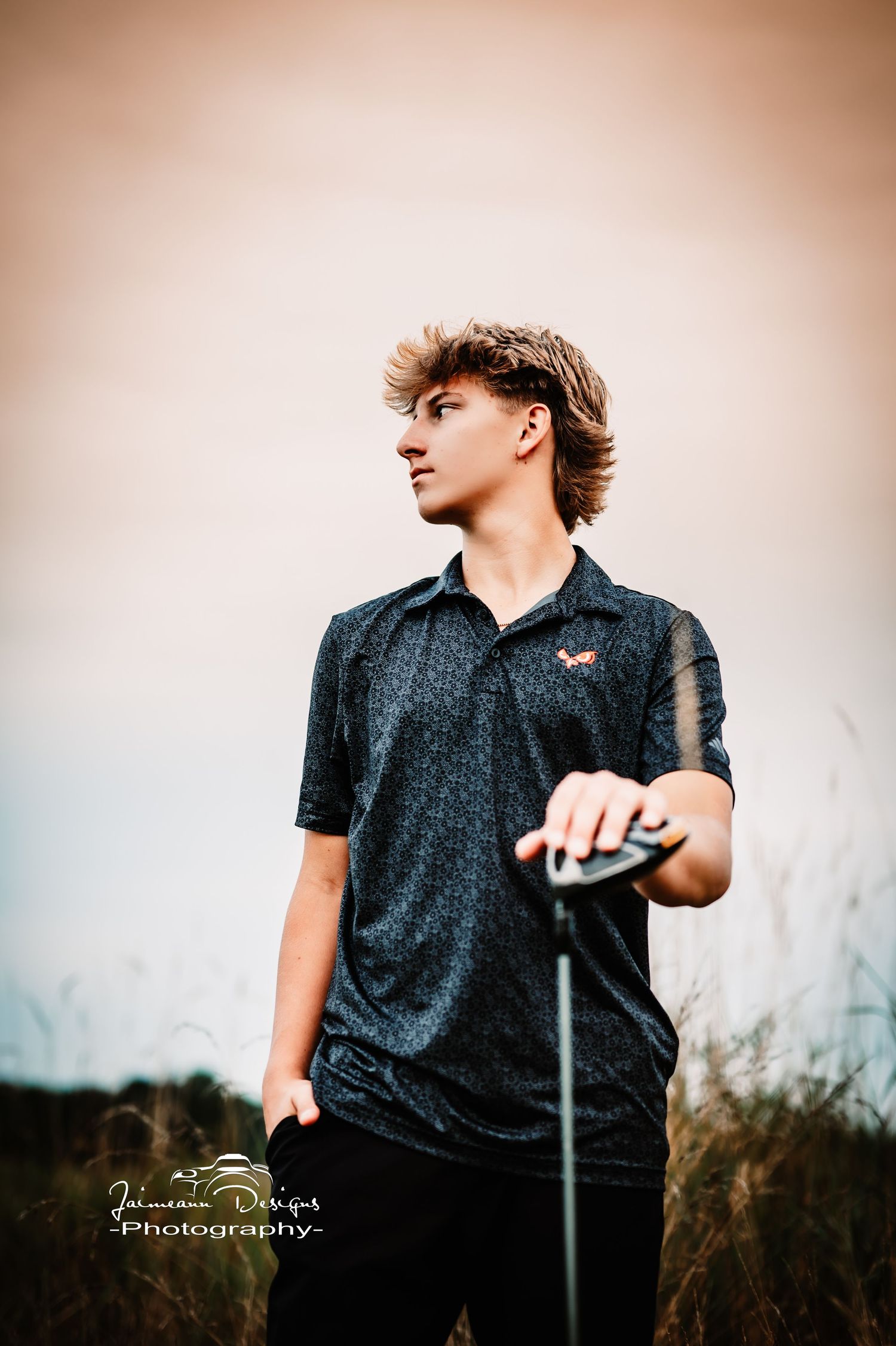 Stylish portrait of golfer in black polo holding club during golden hour.