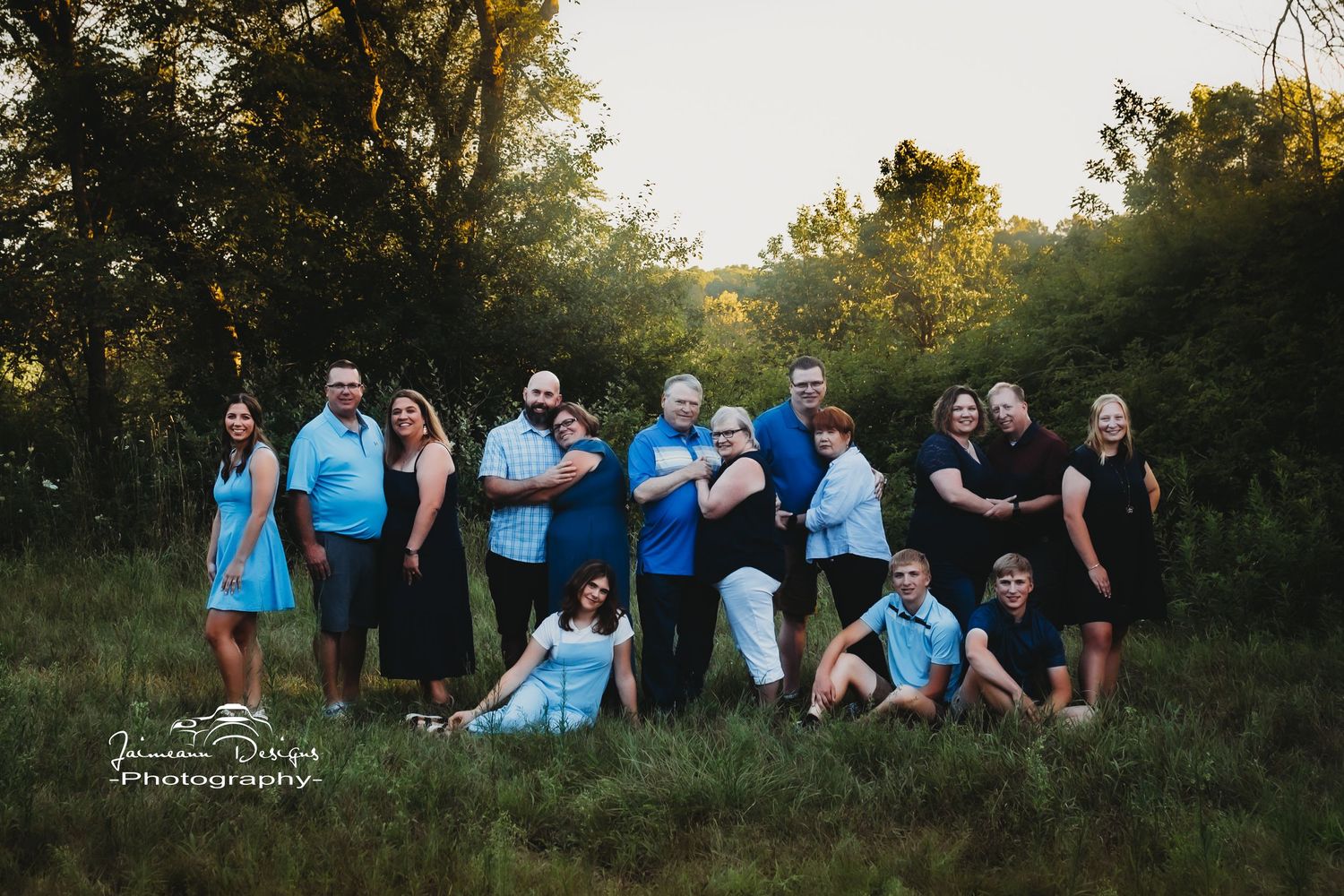 Family group photo with coordinated blue and black outfits in a wooded outdoor setting.