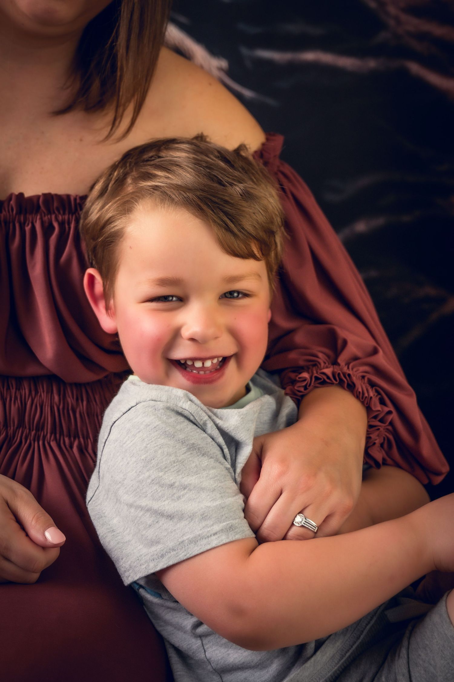 Joyful candid portrait against burgundy fabric with natural lighting.