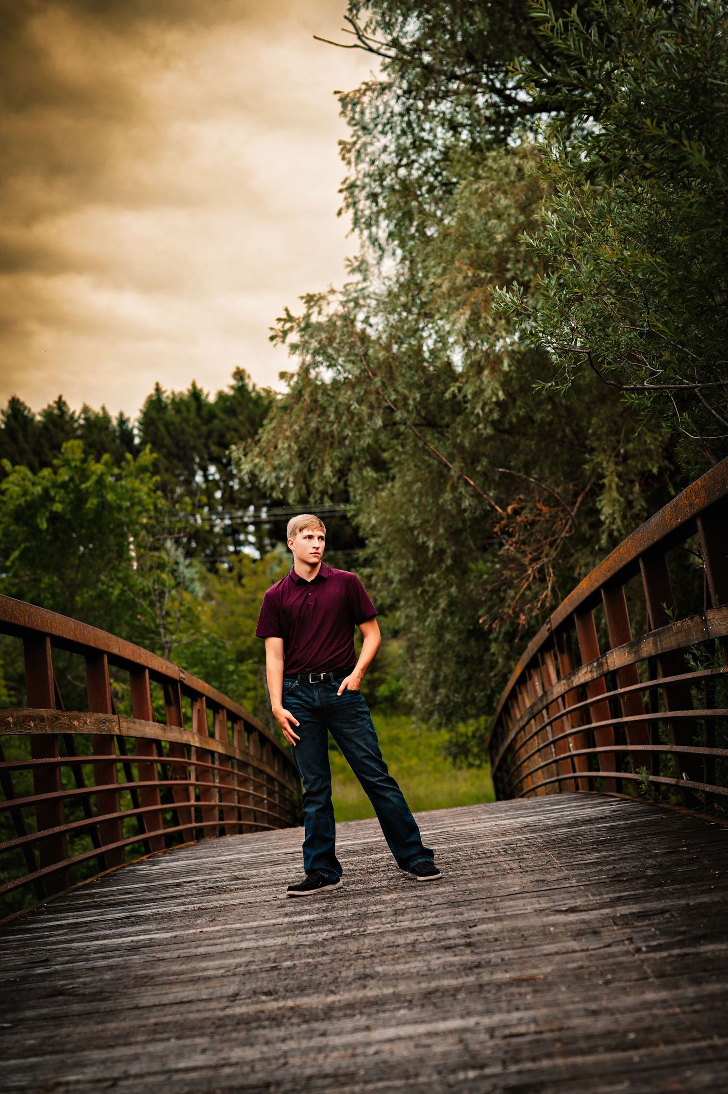 A series of photos showing a person in casual attire posing on a curved wooden footbridge at sunset at private park in Campbellsport, WI